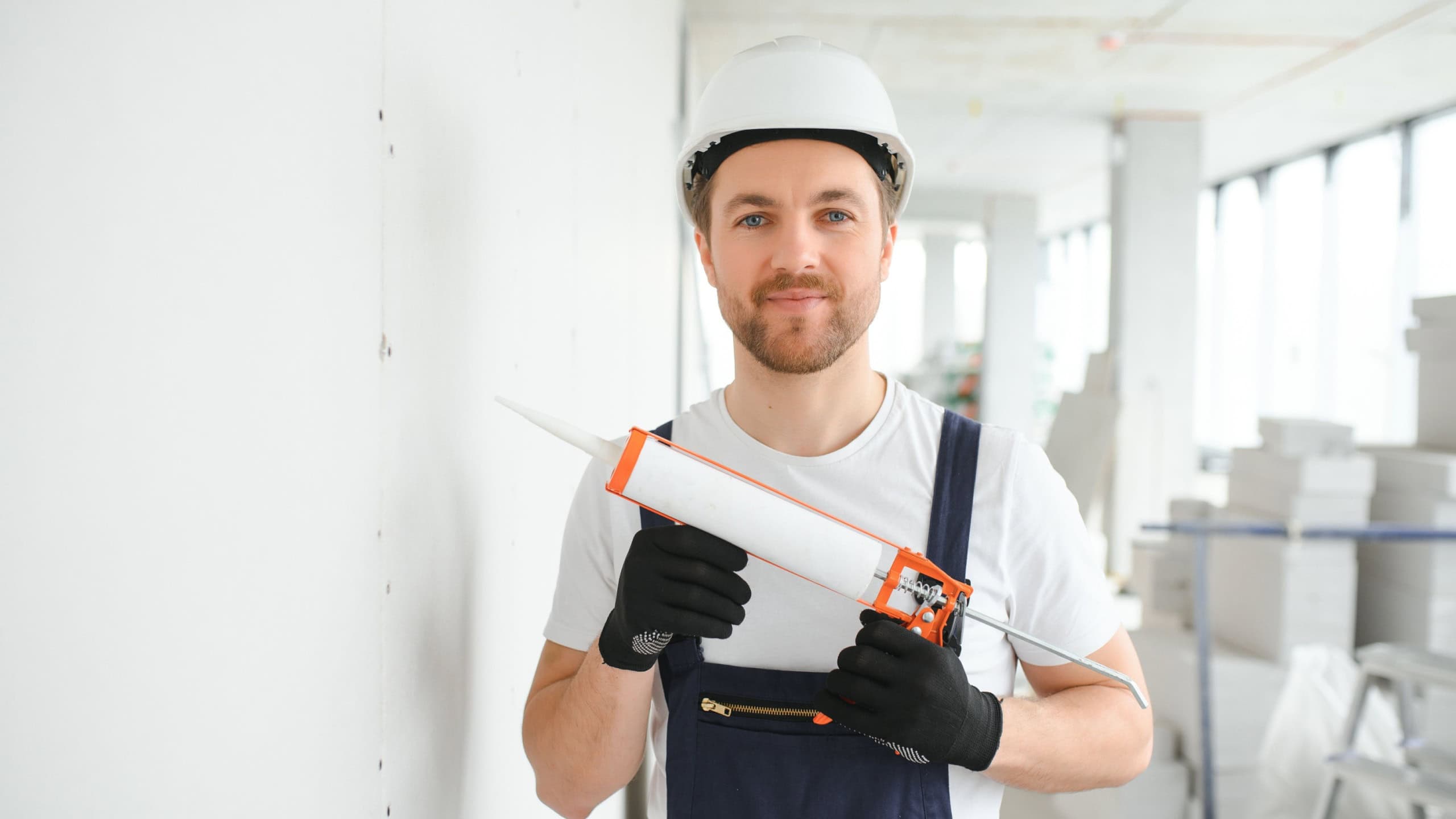 Professional Workman Applying Silicone Sealant With Caulking Gun on the Wall.