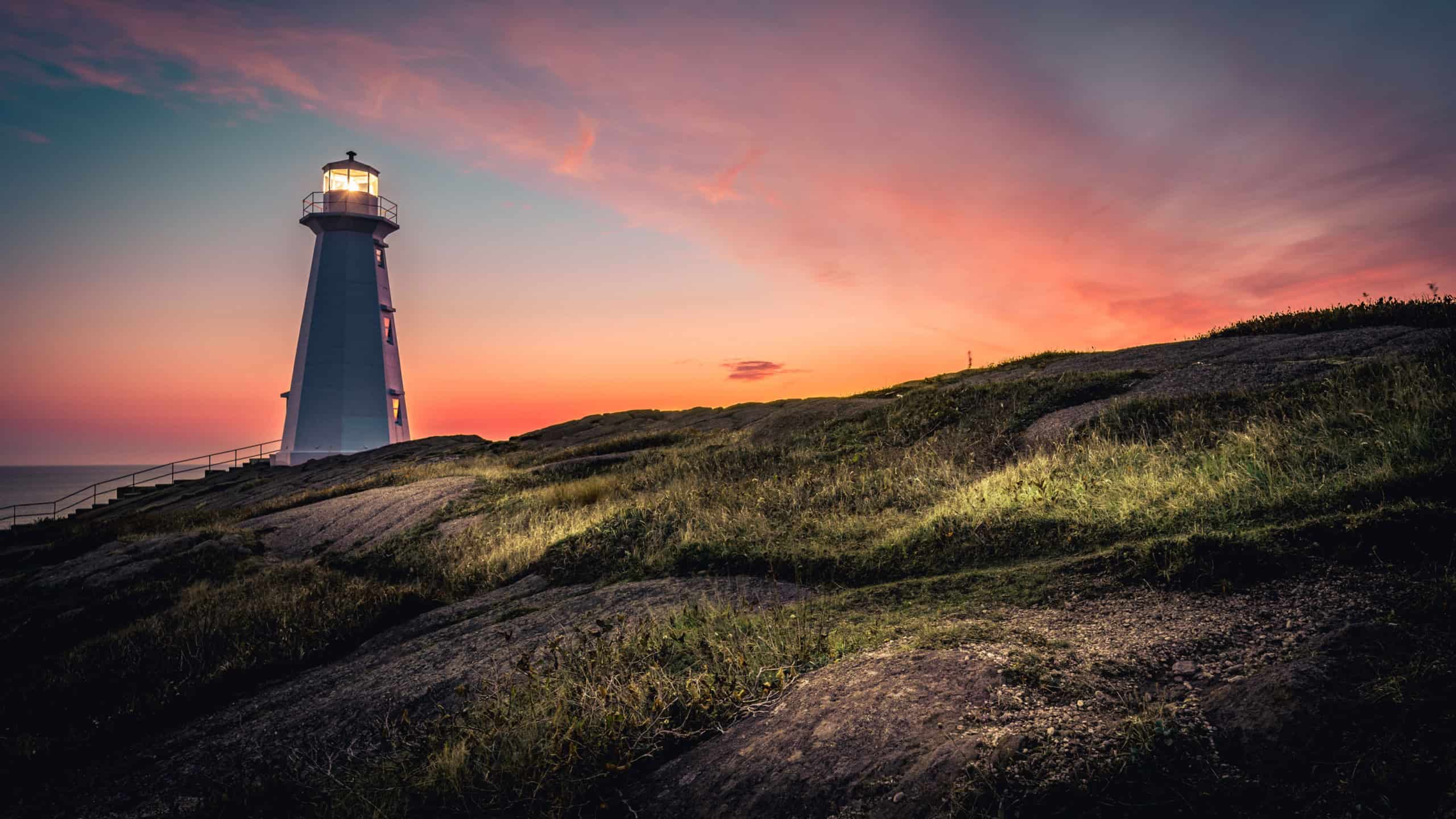 A breathtaking view of Cape Spear Lighthouse on colorful sky background during sunrise