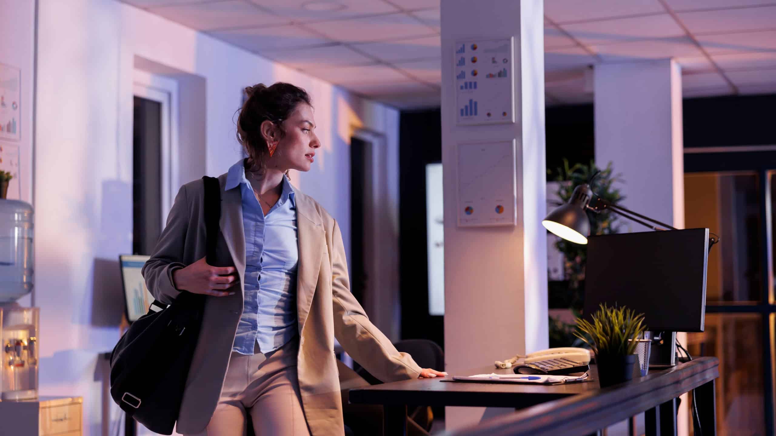Businesswoman finishing company strategy late at night, preparing to leave corporate office. Executive manager working overhours at financial graphs report in startup office. Business concept