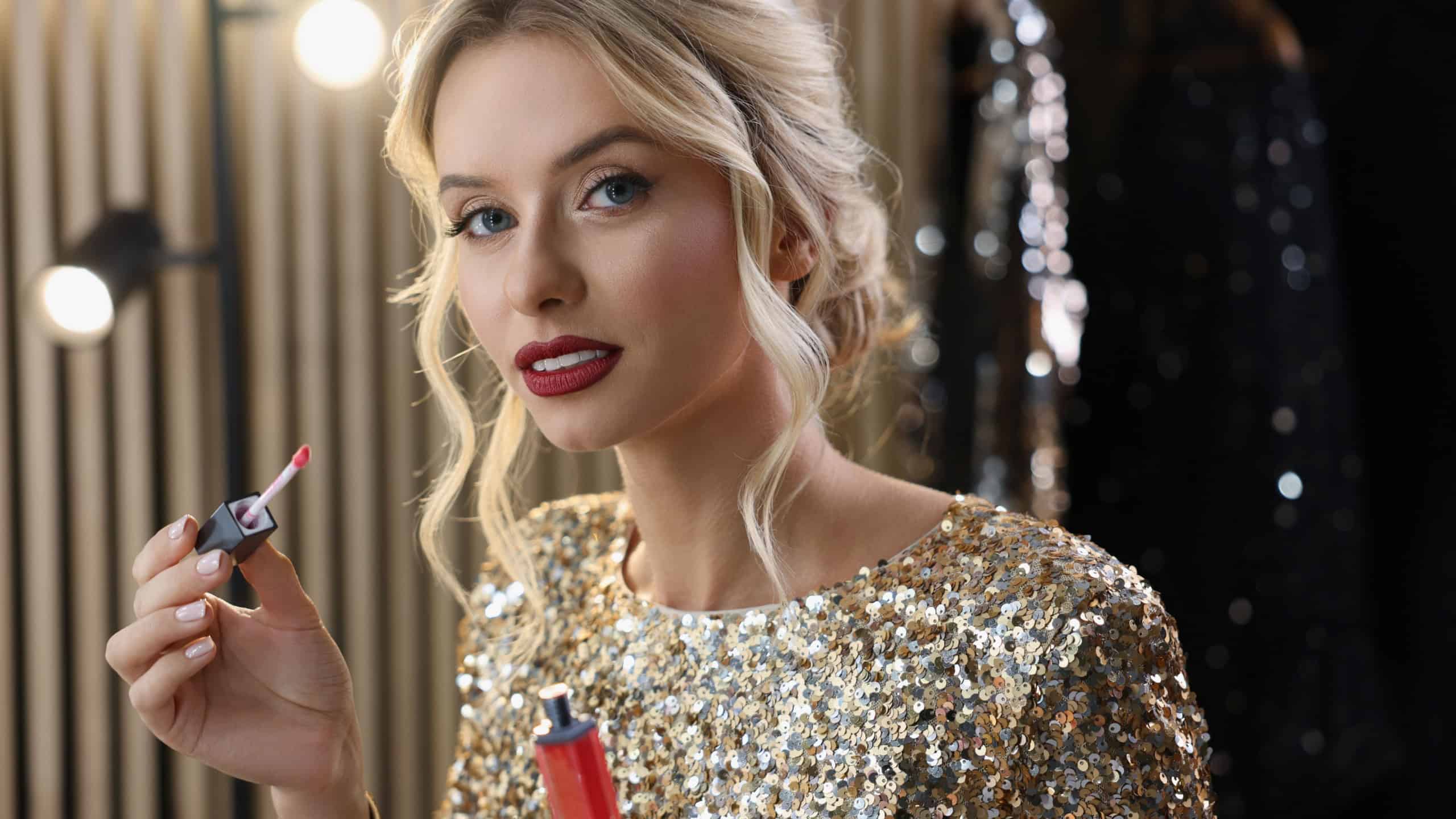 Beautiful makeup. Attractive woman applying lipstick in dressing room