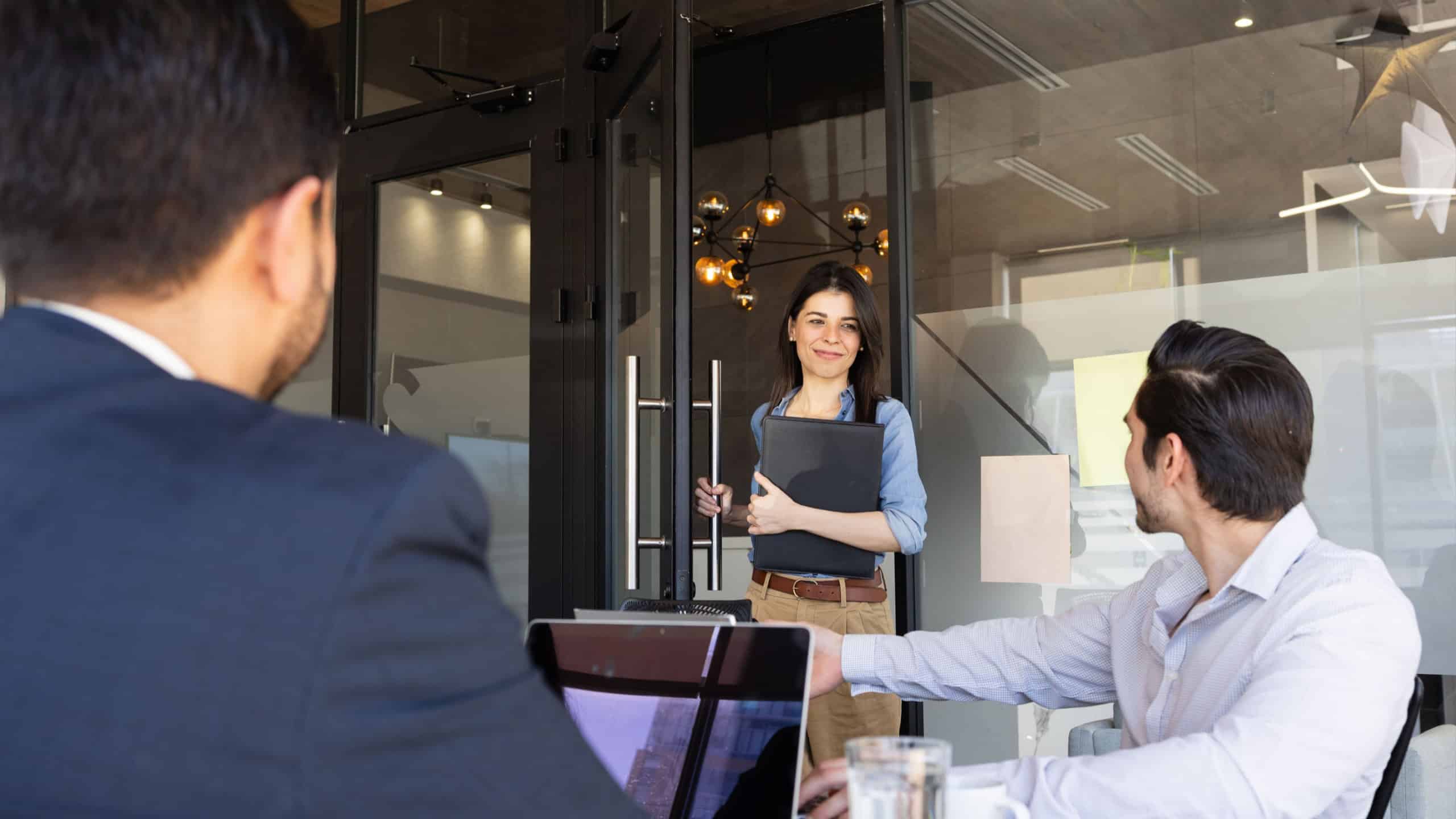 Beautiful businesswoman opening the door of a meeting room and joining a business meeting