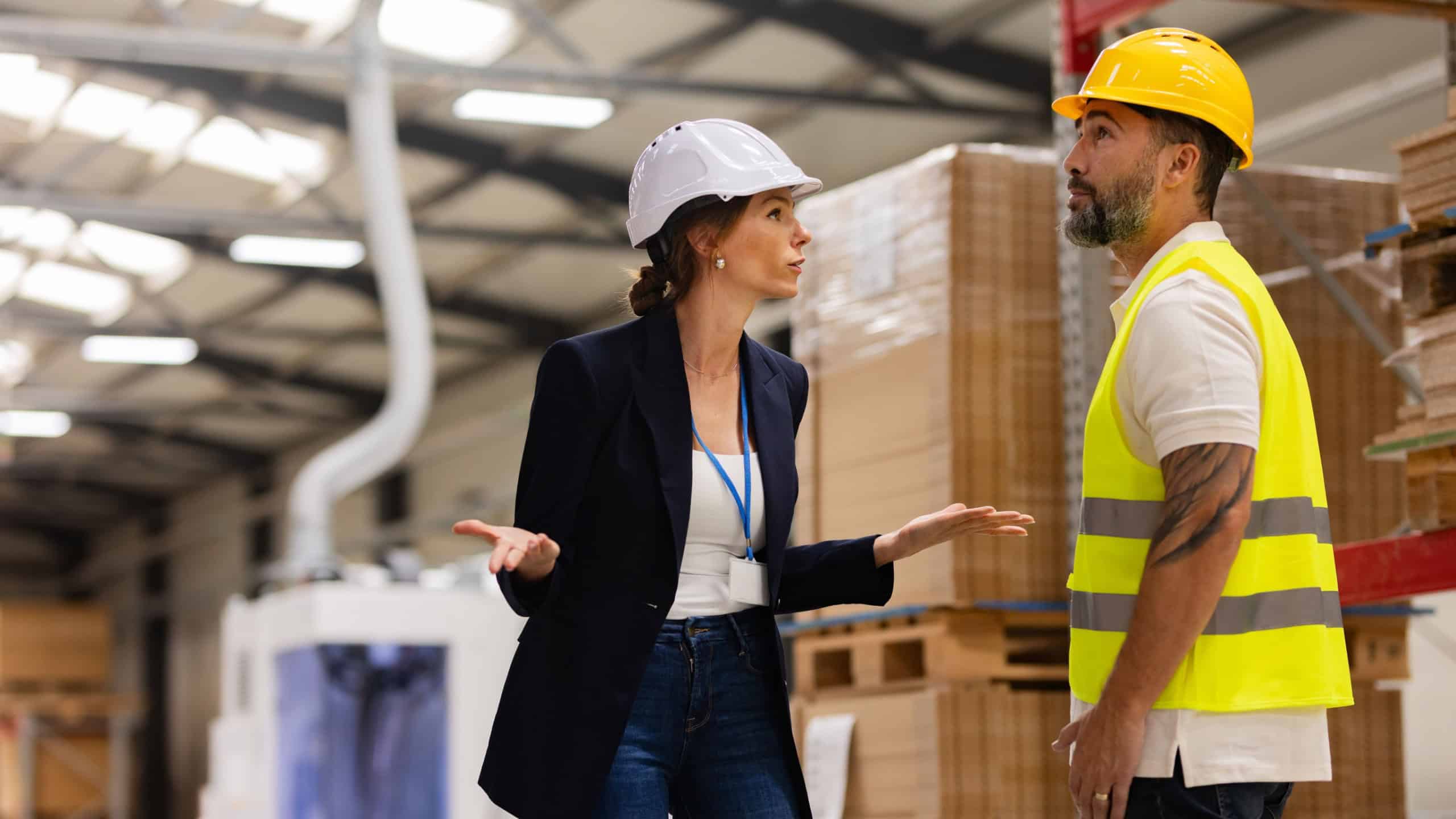 Female manager scolding employee in modern industry factory. Worker making mistake. Production manger is angry, dissatisfied for worker's poor quality work, safety viaolations.