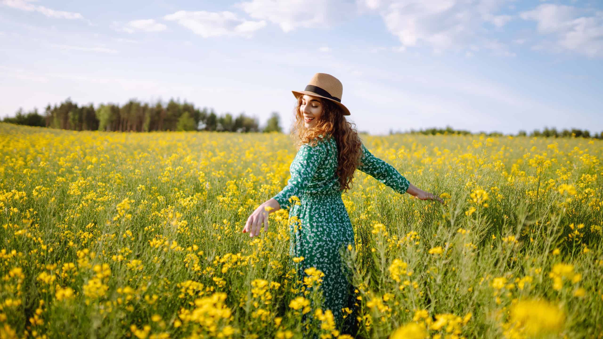 Happy woman walking in flowering field. Fashion, beauty concept. Summer landscape.