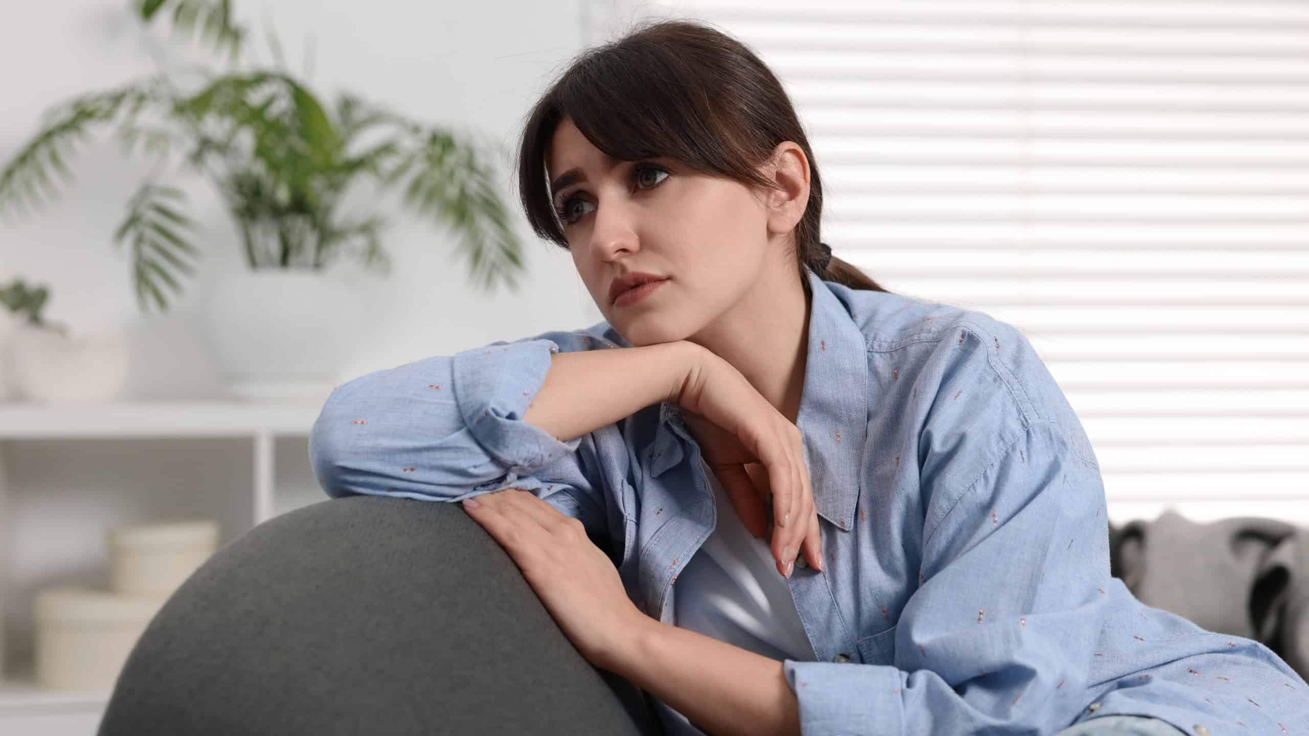 Loneliness concept. Sad woman sitting on sofa at home