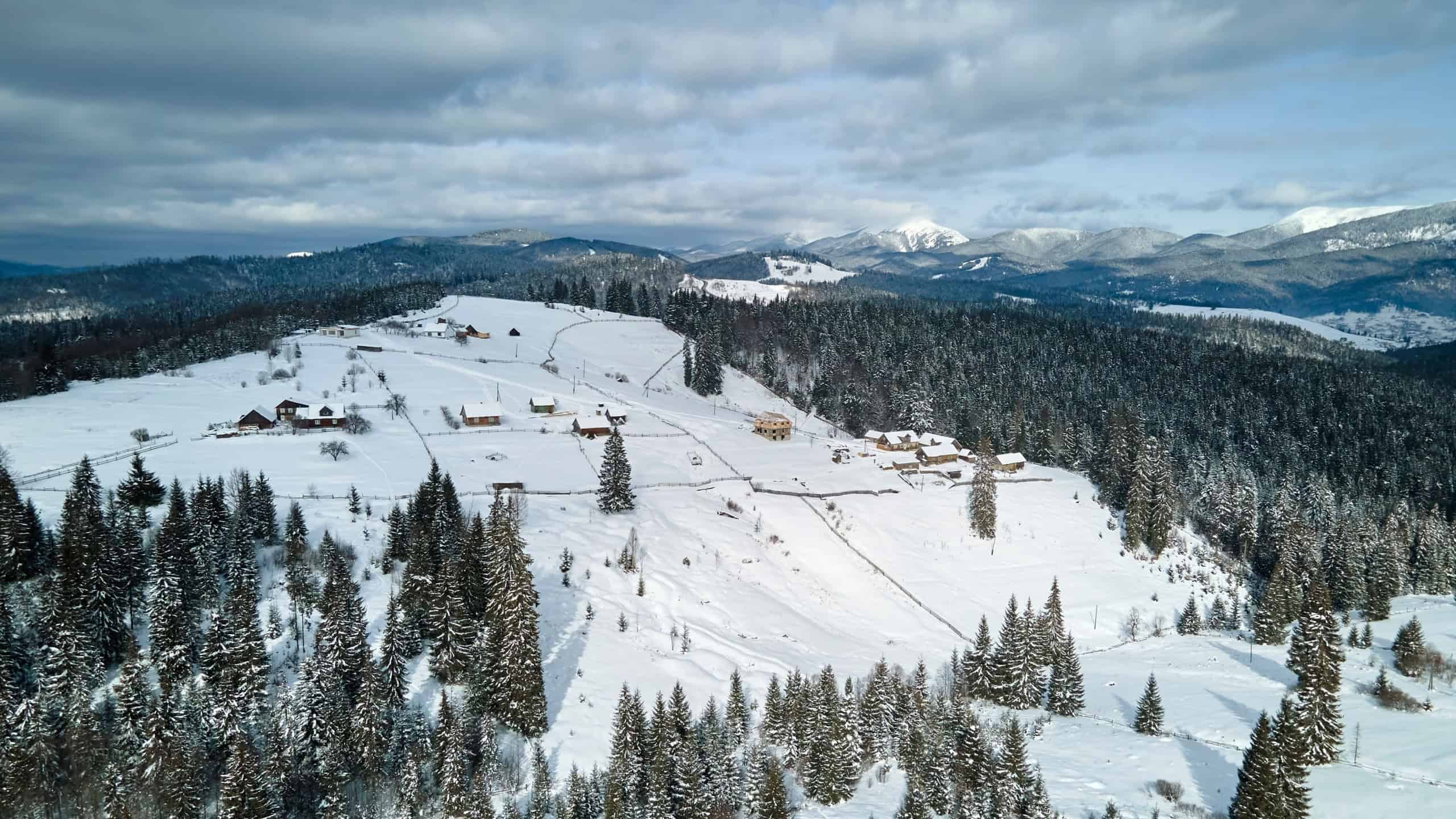 Winter landscape with small village houses between snow covered forest in cold mountains
