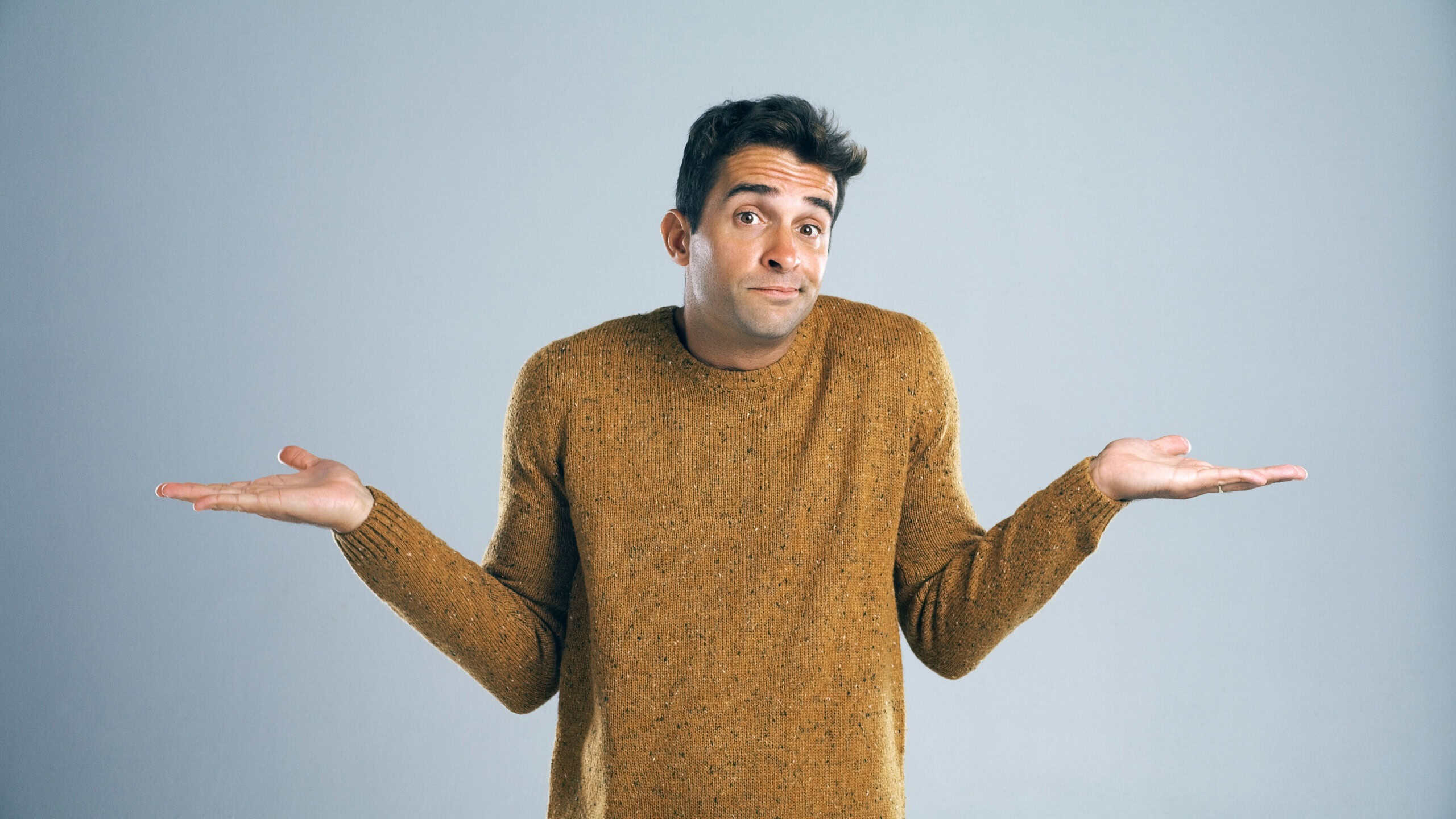 Man, portrait and unsure with hands in studio for question, confused or doubt with decision on mockup space. Person, choice or scale for options with comparison, shrug or uncertain on gray background