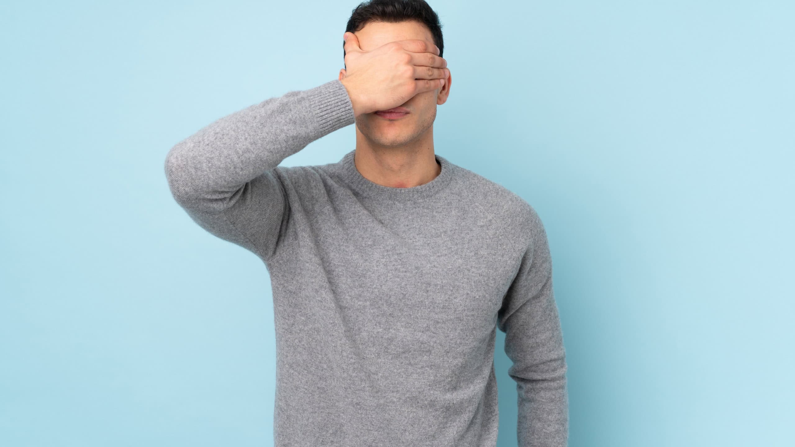 Young caucasian handsome man isolated on blue background covering eyes by hands