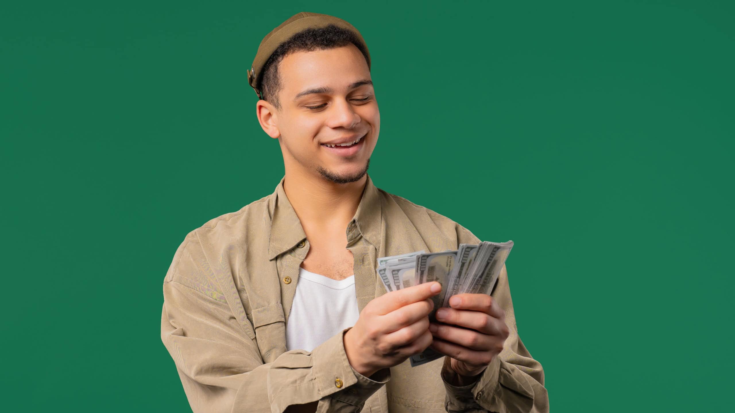 Rich african american man with Usd money on green background. Young Guy Or Student counting salary, scholarship payment. Jackpot, win. High quality photo