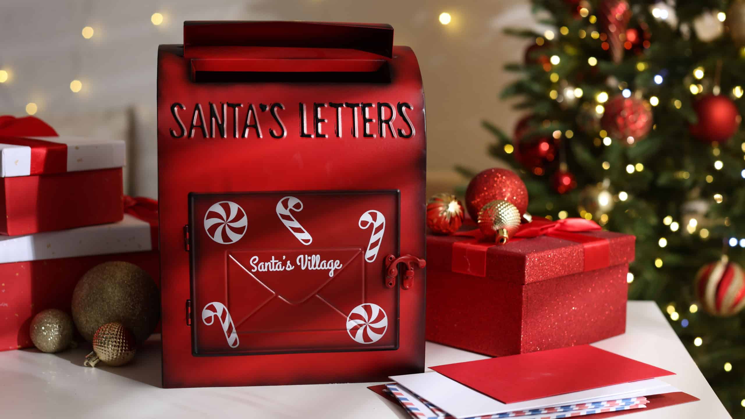 Santa Claus mailbox, letters, gift boxes and Christmas decor on white table indoors