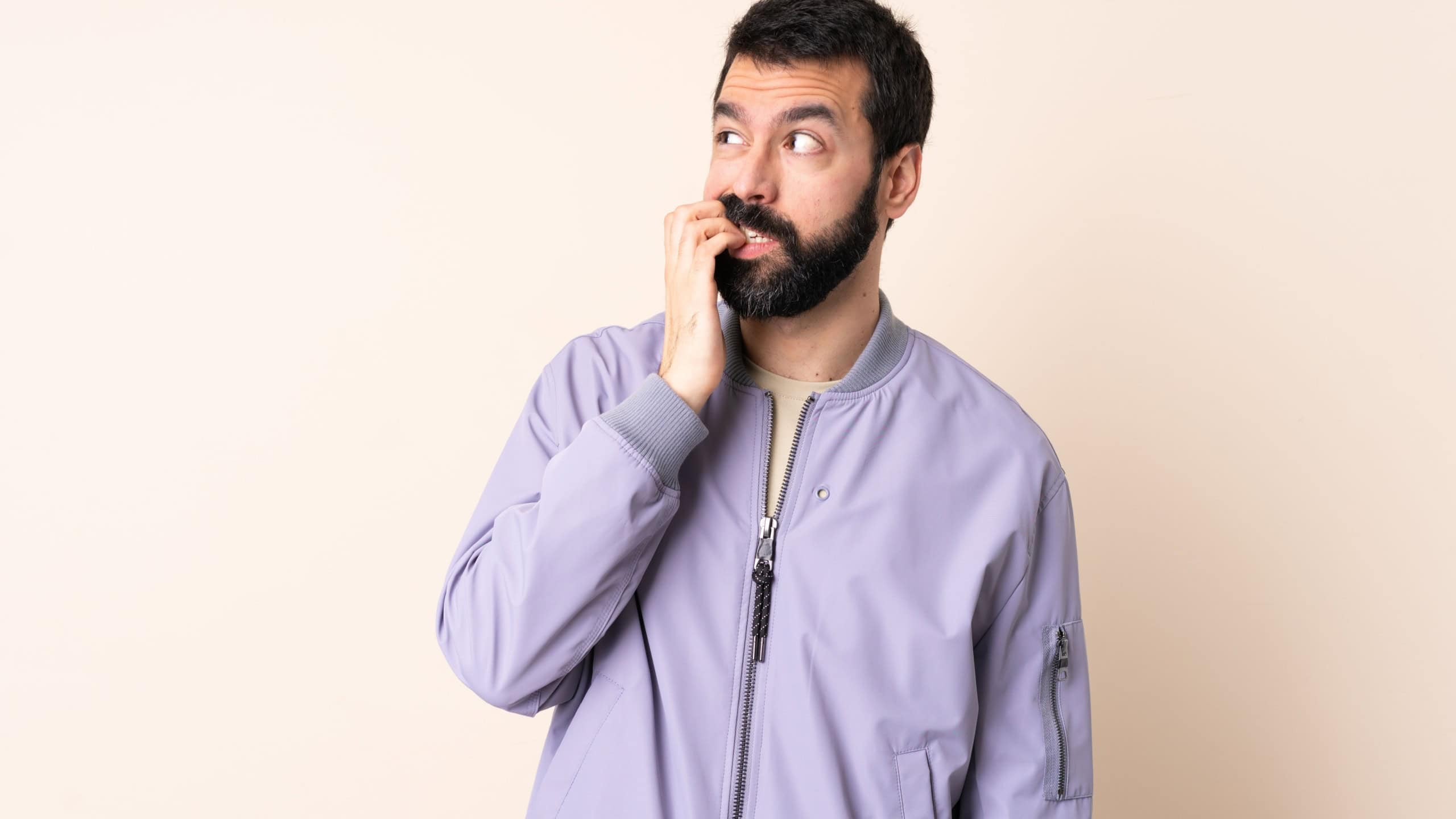 Caucasian man with beard wearing a jacket over isolated background is a little bit nervous