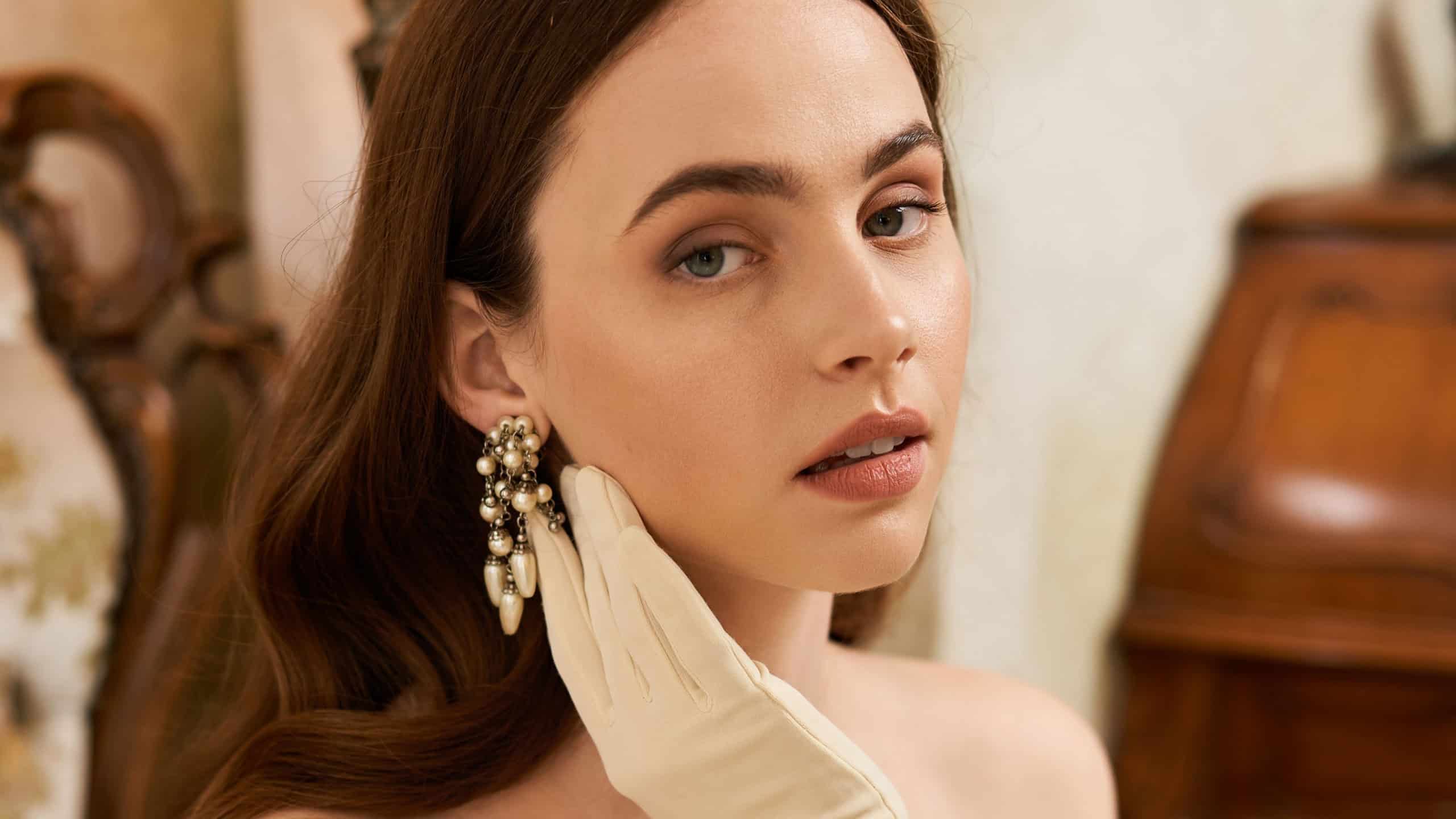 A striking young woman showcases vintage elegance while gracefully posing in a luxurious room.