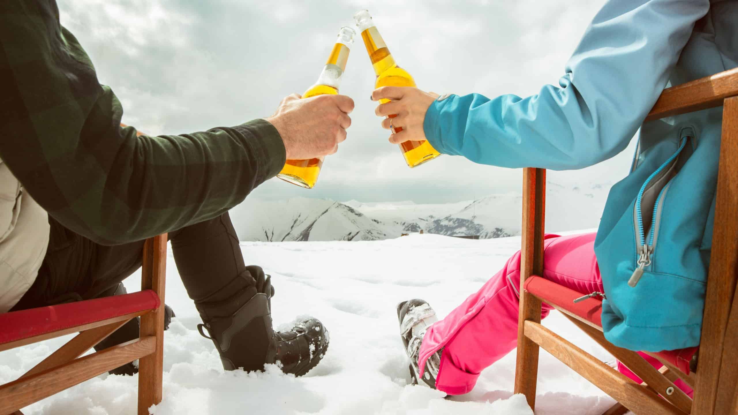 Couple relax sit on chairs in snowy ski resort with beer bottle, concept of leisure, winter holiday, relaxation, carefree lifestyle, freedom, cozy outdoor relaxation moment