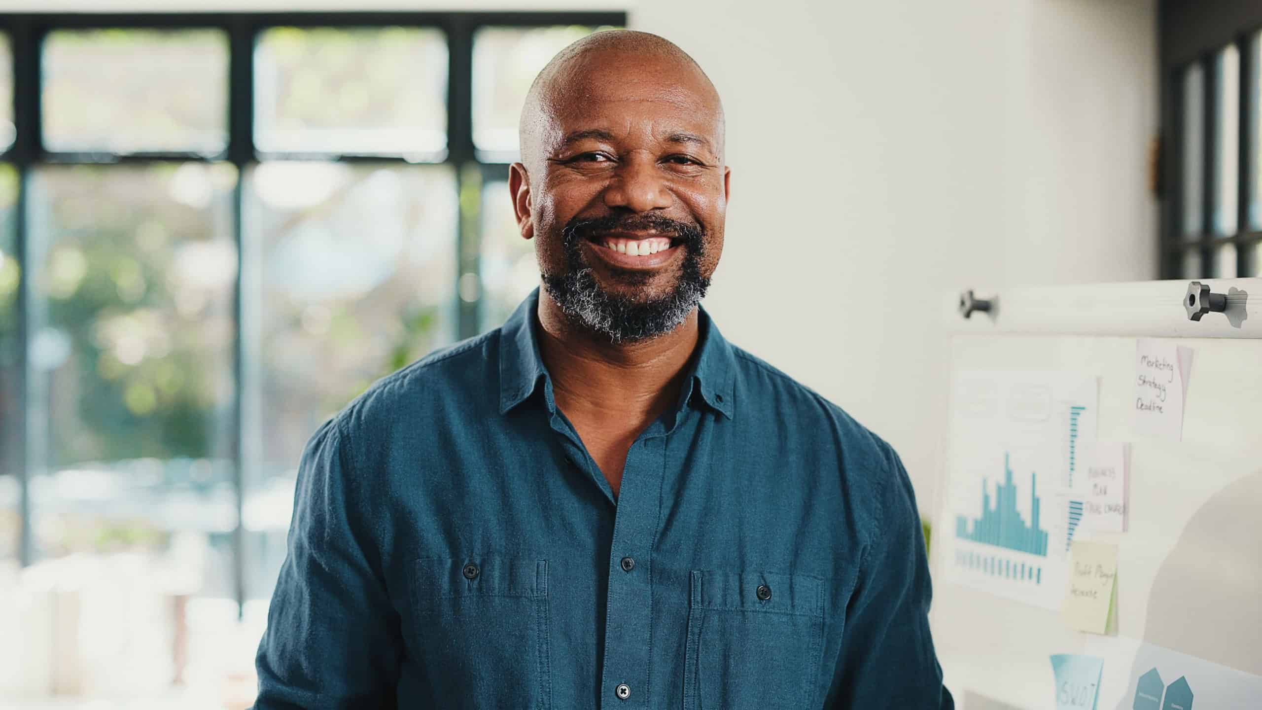 Pride, portrait and mature businessman in office with statistics for corporate finance project. Happy, professional and African male financial manager with smile for company about us in workplace.