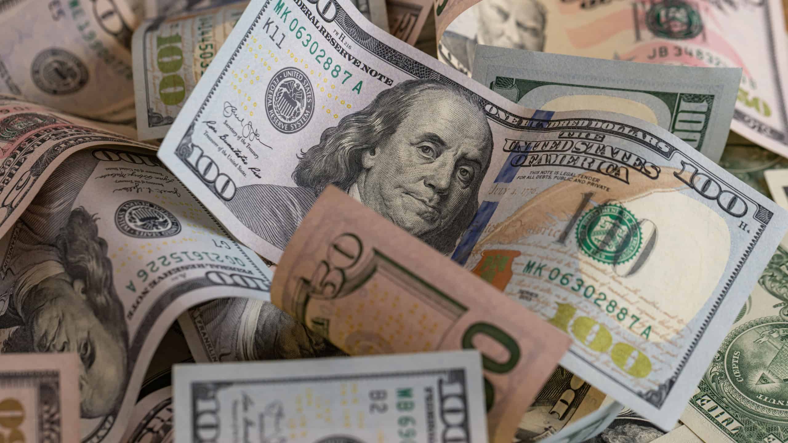 Scattered US Dollar Banknotes Background with Focus on Hundred Dollar Bill