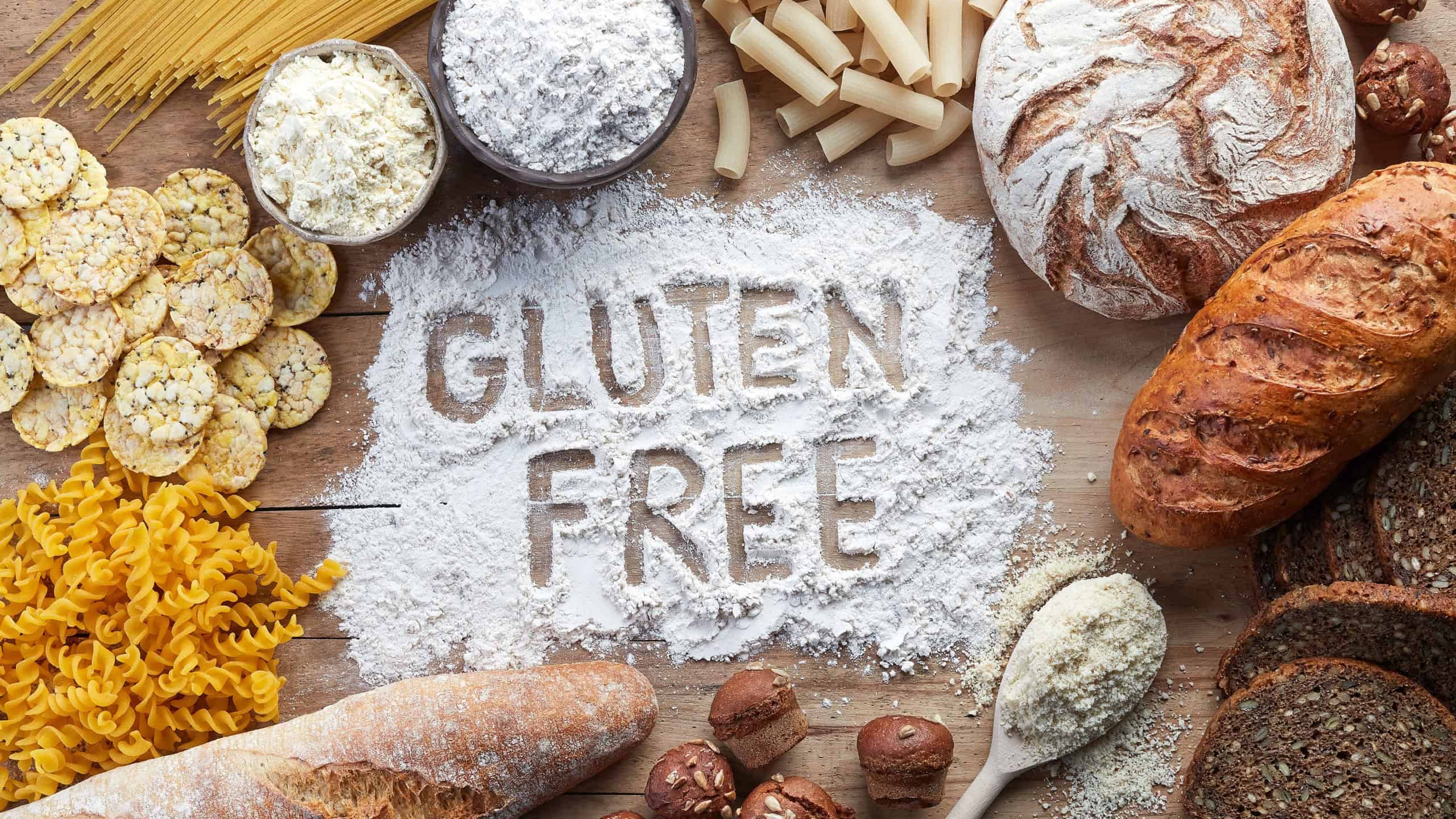 Gluten free food. Various pasta, bread, snacks and flour on wooden background from top view