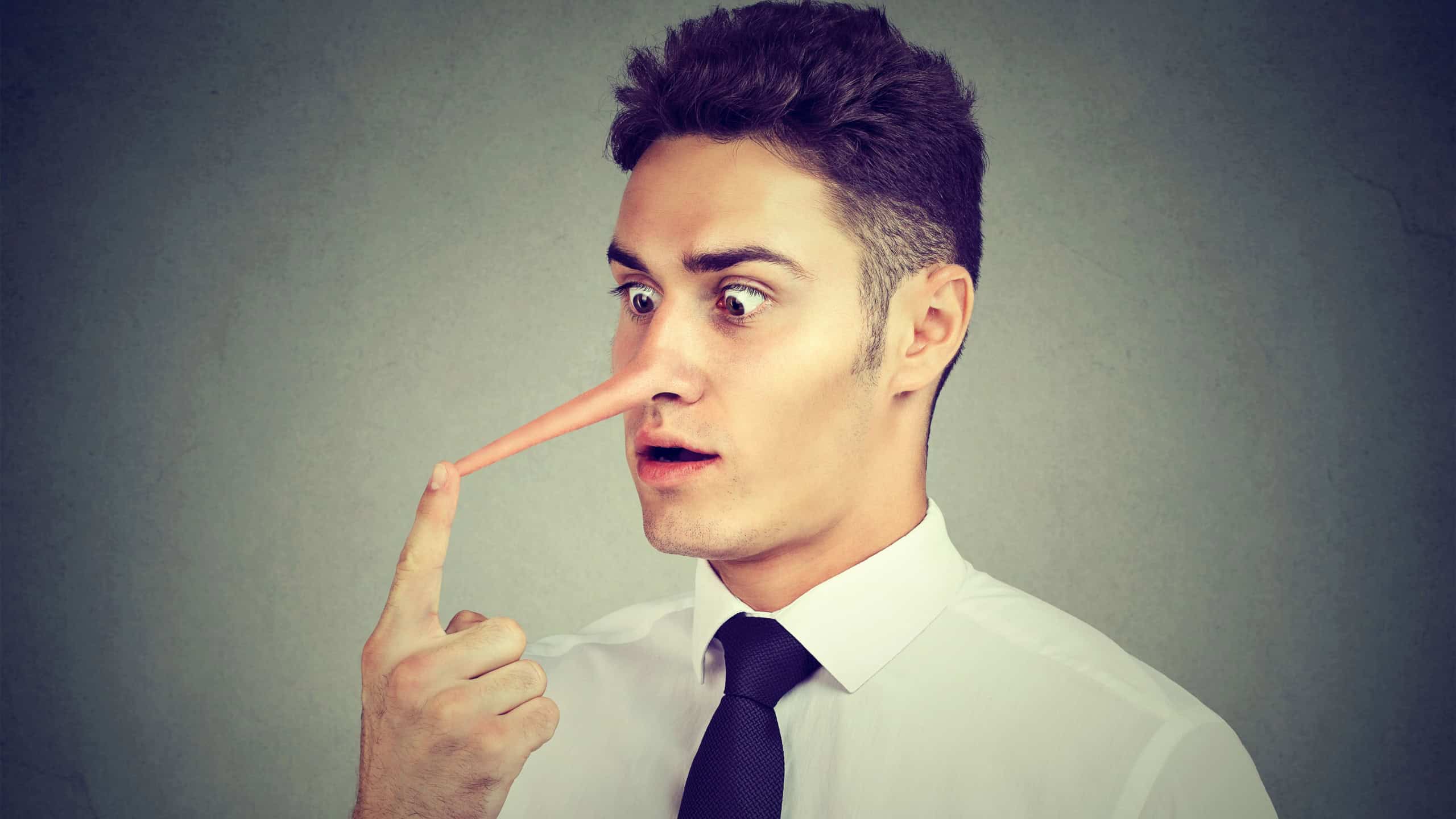 Business man with long nose isolated on grey wall background. Liar concept.