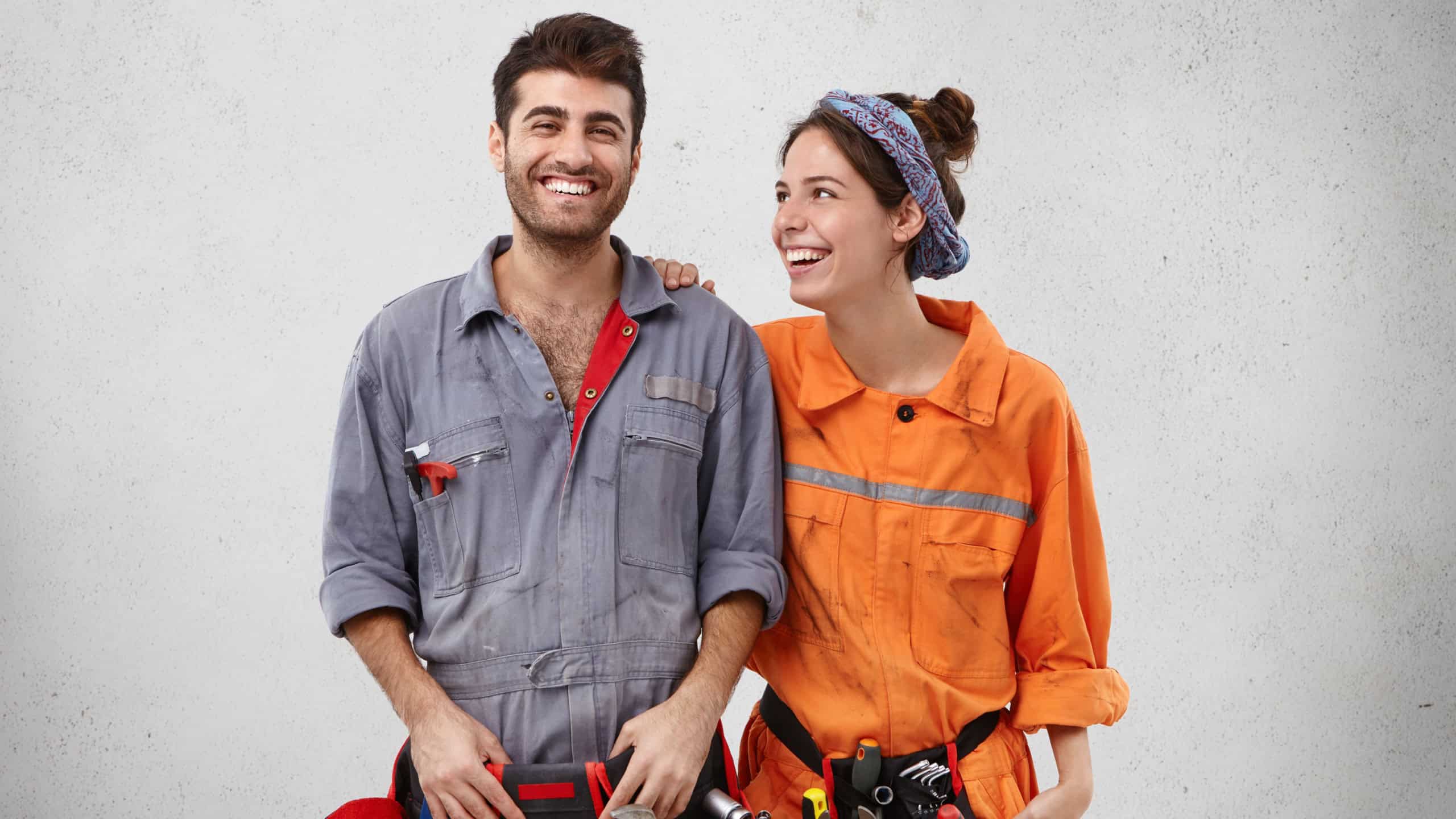 Joyful handyman being glad to repair car, recieves support from wife, rejoice promotion at work. Service workers have many clients. Smiling woman and man work of bilduing team, construct something