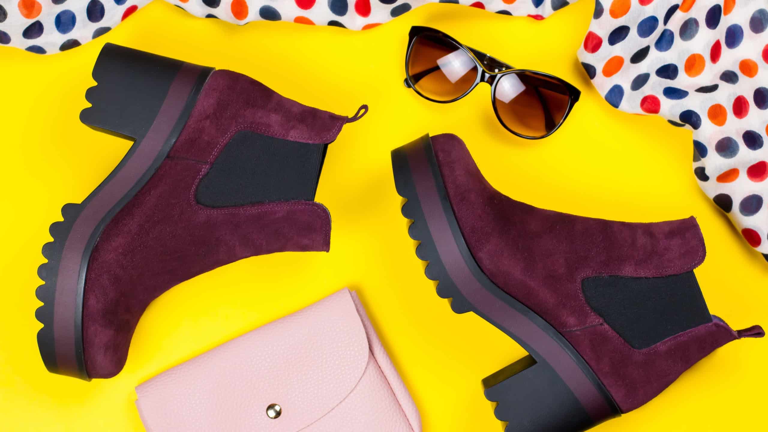 Stylish purple ankle boots, pink purse, sunglasses and printed scarf