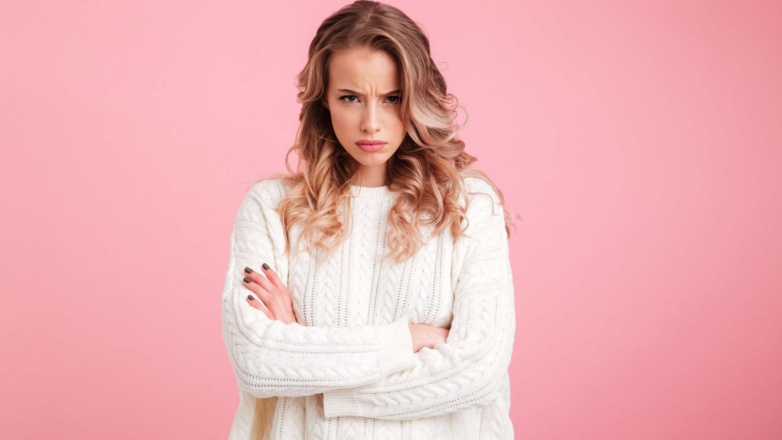 Picture of angry young woman standing isolated over pink background. Looking camera.