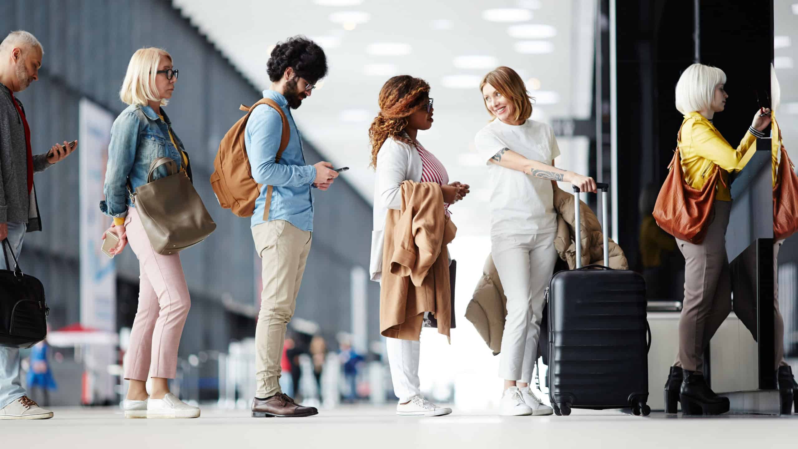 Several passengers standing in queue while waiting for check-in registration before flight