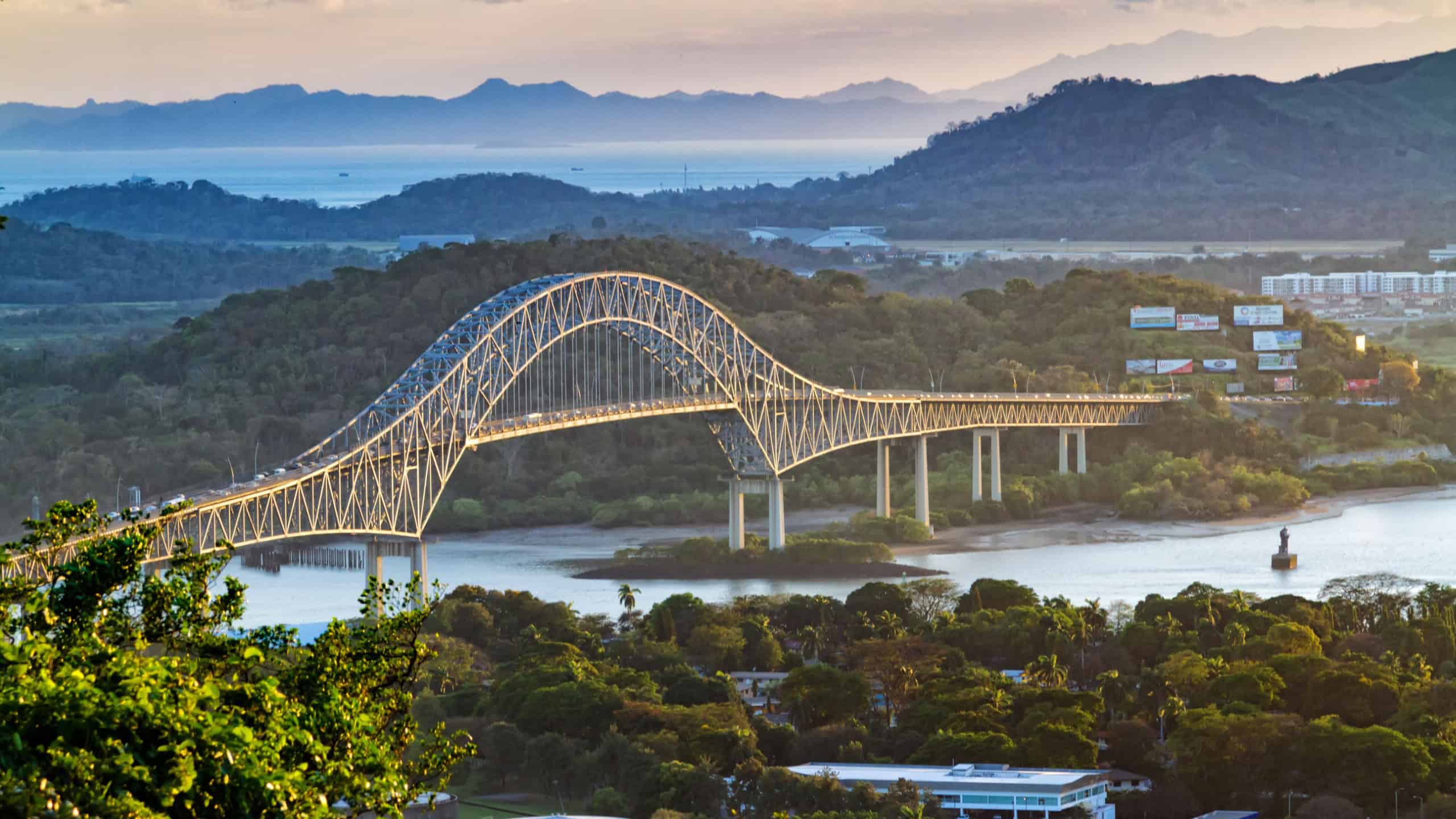Panoramic aerial view of the Bridge of The Americas over the Panama Canal Pacific Entrance. Sunset scene with a gentle mist in the background. The bridge is spanning two continents - two Americas.