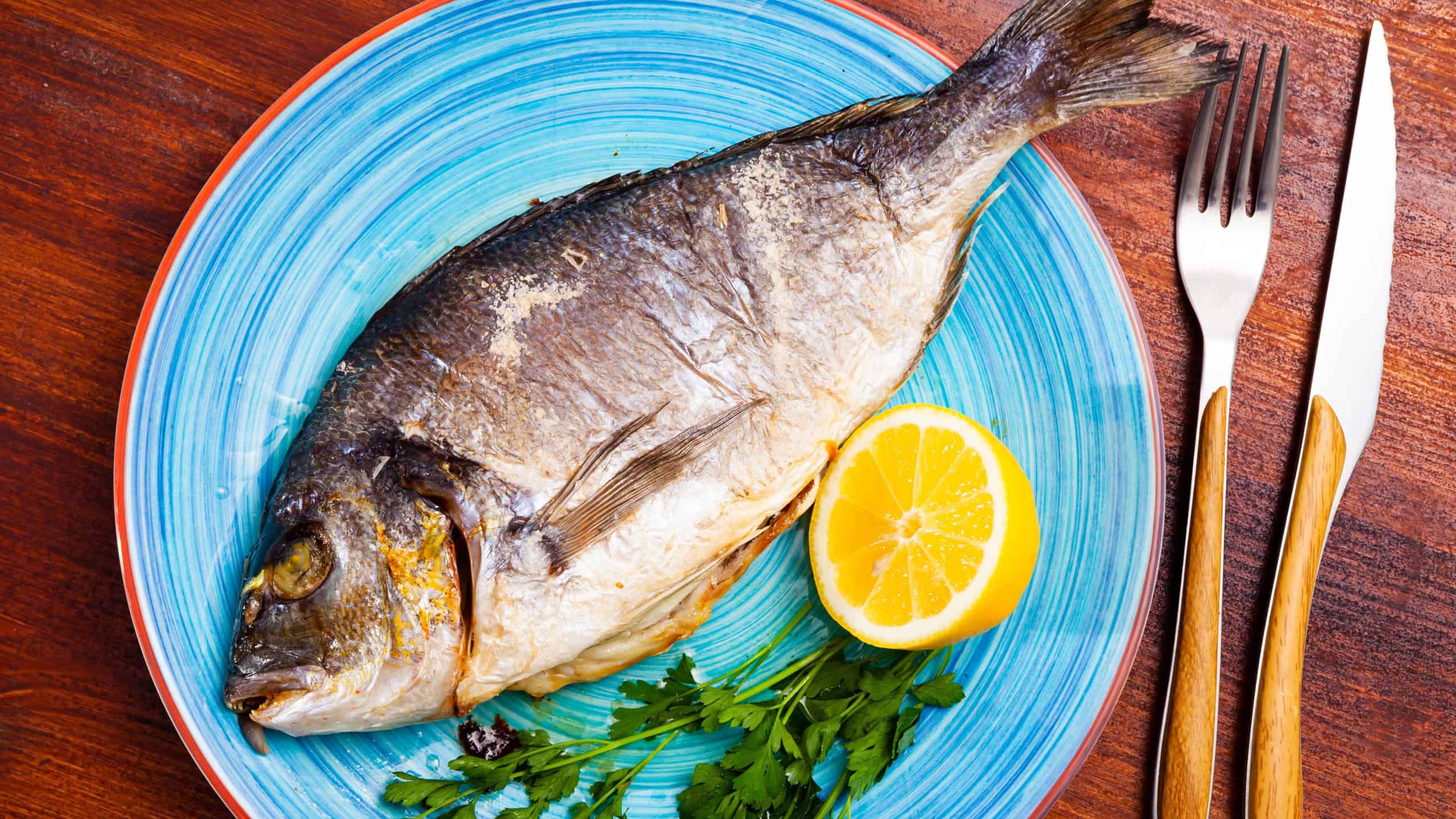 Baked in oven dorado fish with orange on plate
