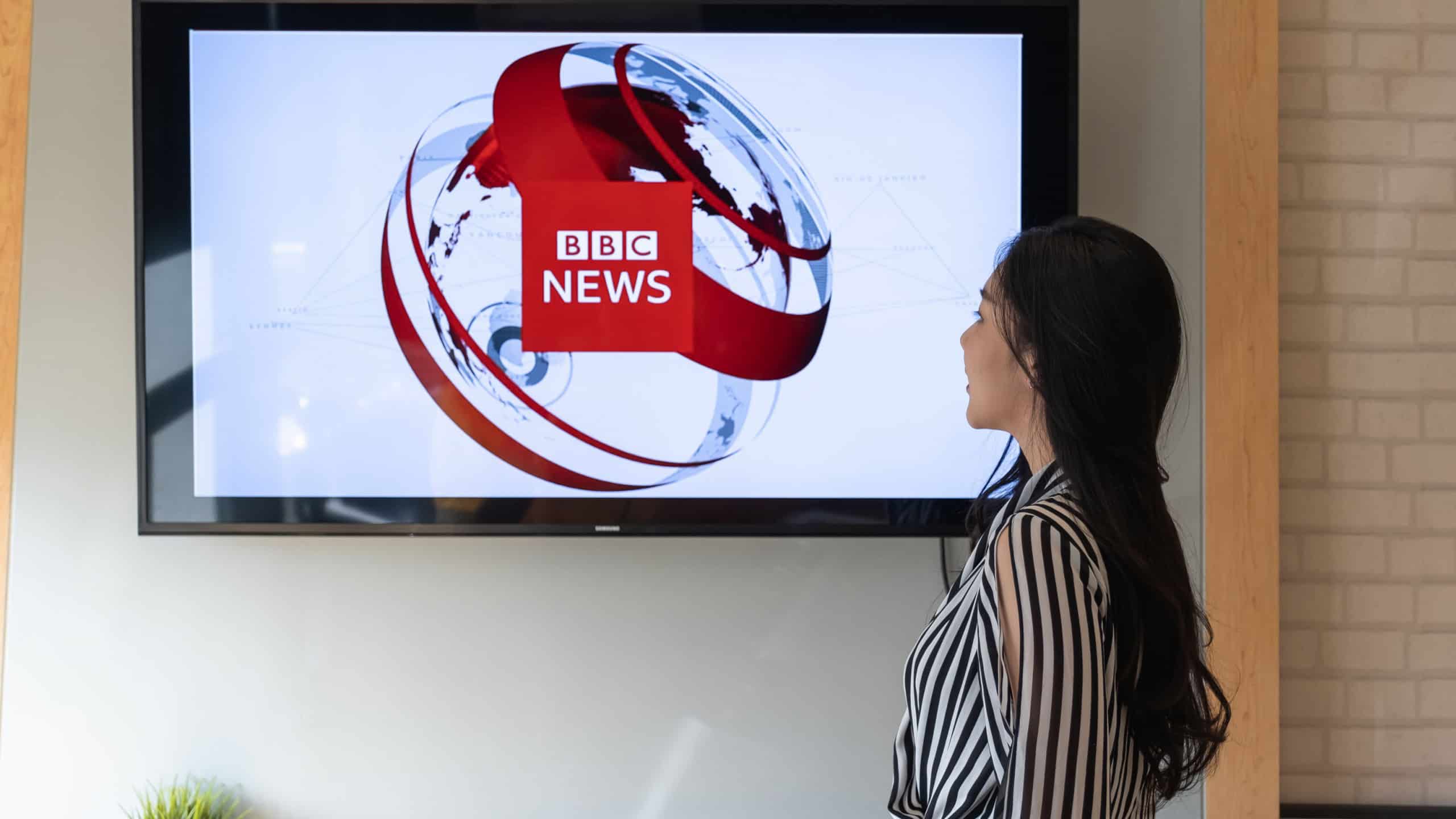 Woman watching BBC News on TV. BBC News reporting a breaking news item