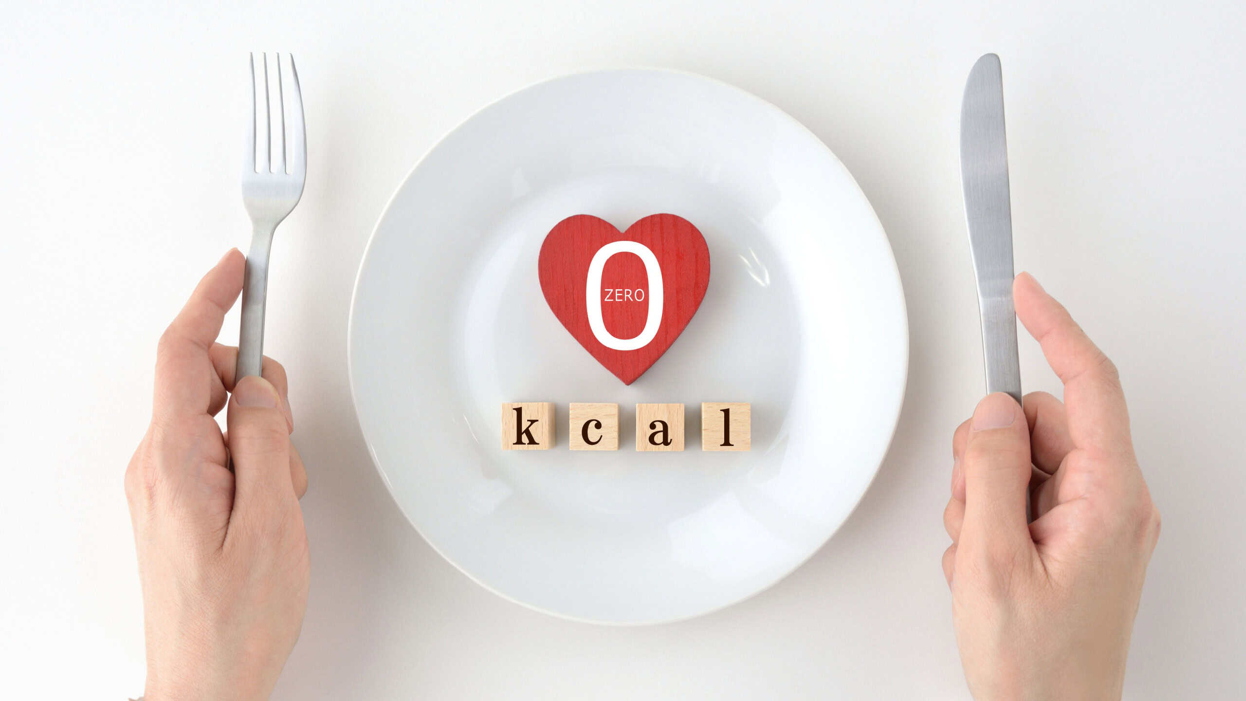 Heart object and wooden blocks with 0 kcal word on white plate