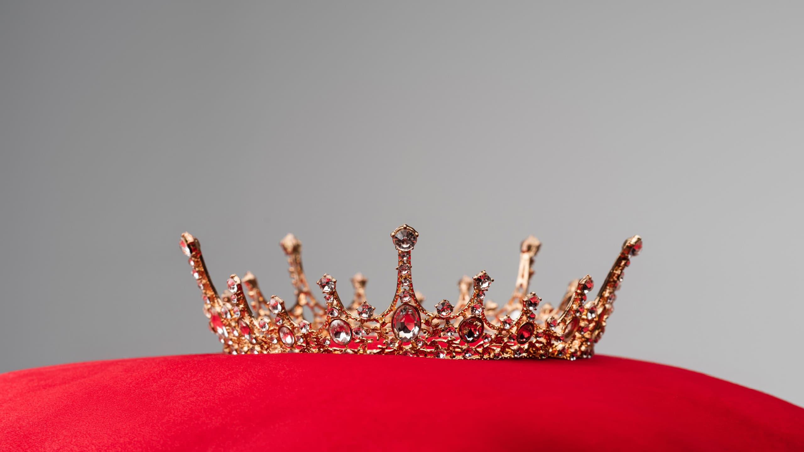 Royal crown on red velvet cushion isolated on grey