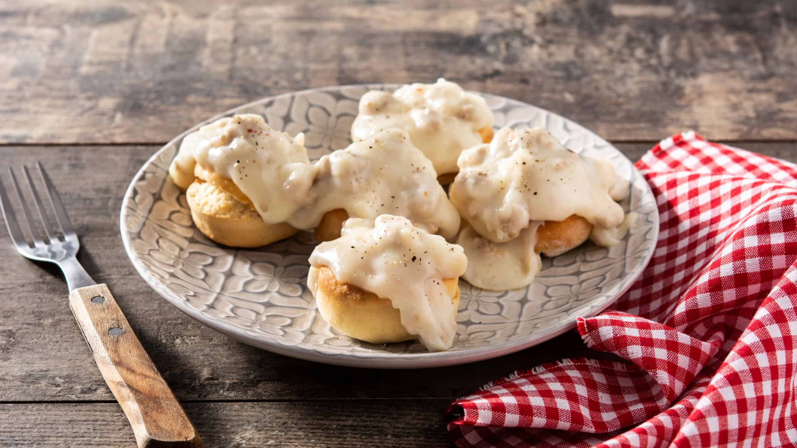 Traditional American biscuits and gravy for breakfast on wooden table