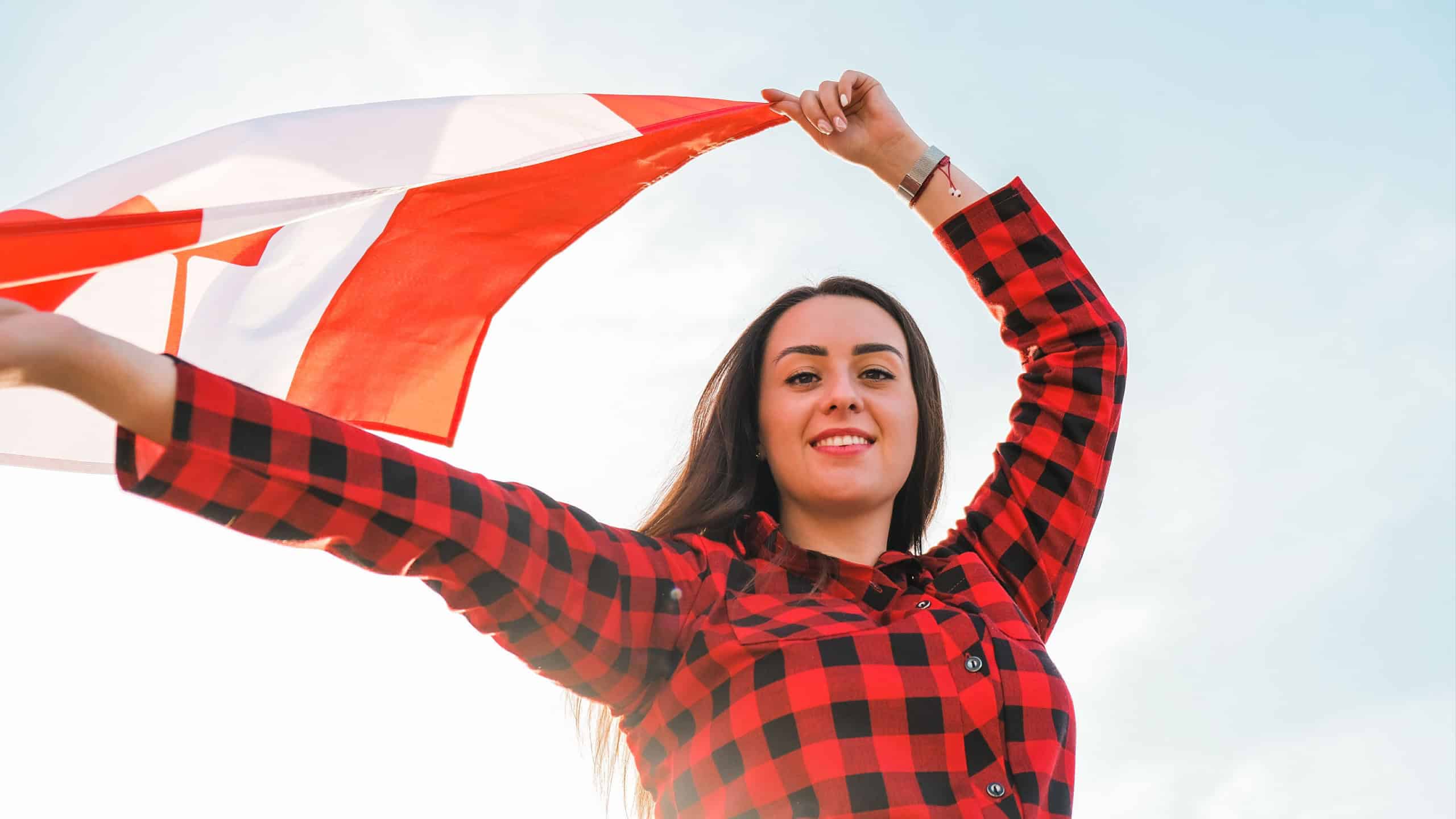 Young millennial brunette woman holding The National Flag of Canada. Canadian Flag or the Maple Leaf. Tourist traveler or patriotism. Immigrant in a free country. Independence day 1th july. Canada day