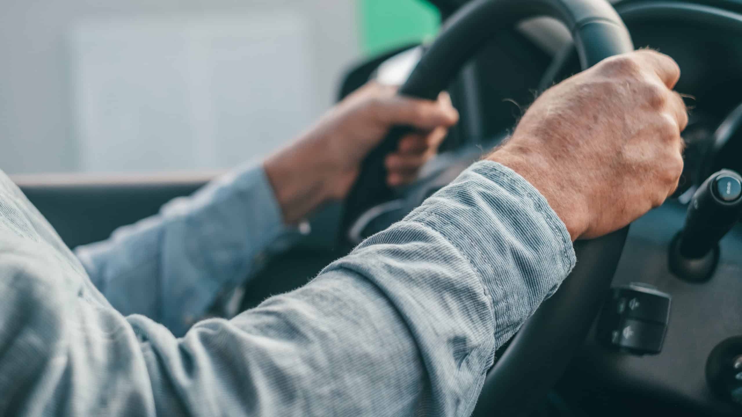 Close up and portrait of old and retired man holding steering wheel with his hands driving and enjoying new car in the road. Satisfied client concept