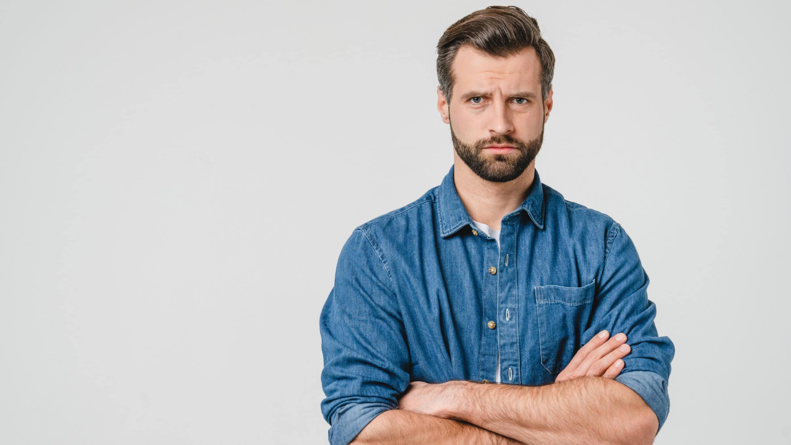 Offended sad angry caucasian young man with arms crossed blowing his lips looking at camera isolated in white background. Conflict anger concept