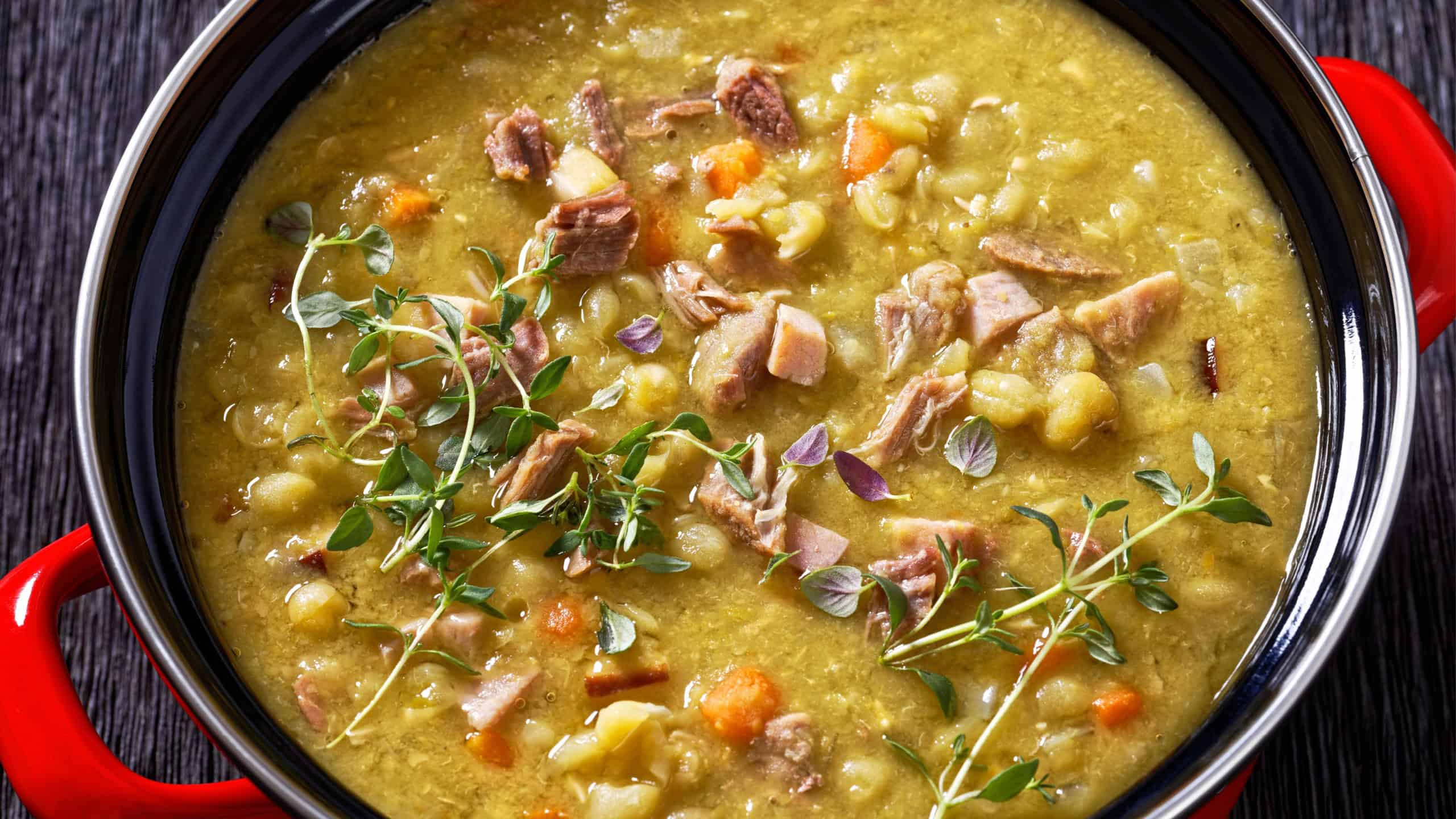 close-up of Finnish split pea soup Hernekeitto with ham on red pot