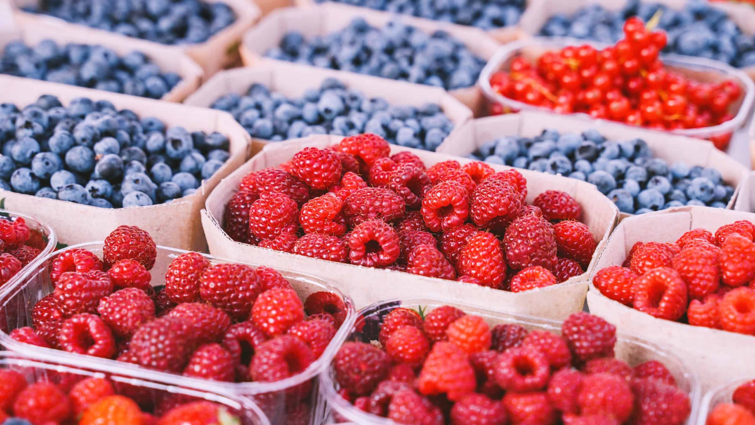 Mixed berries at local market. Close-up of various berries: strawberries, raspberries, blackberries, blueberries, blueberries on shop counter.