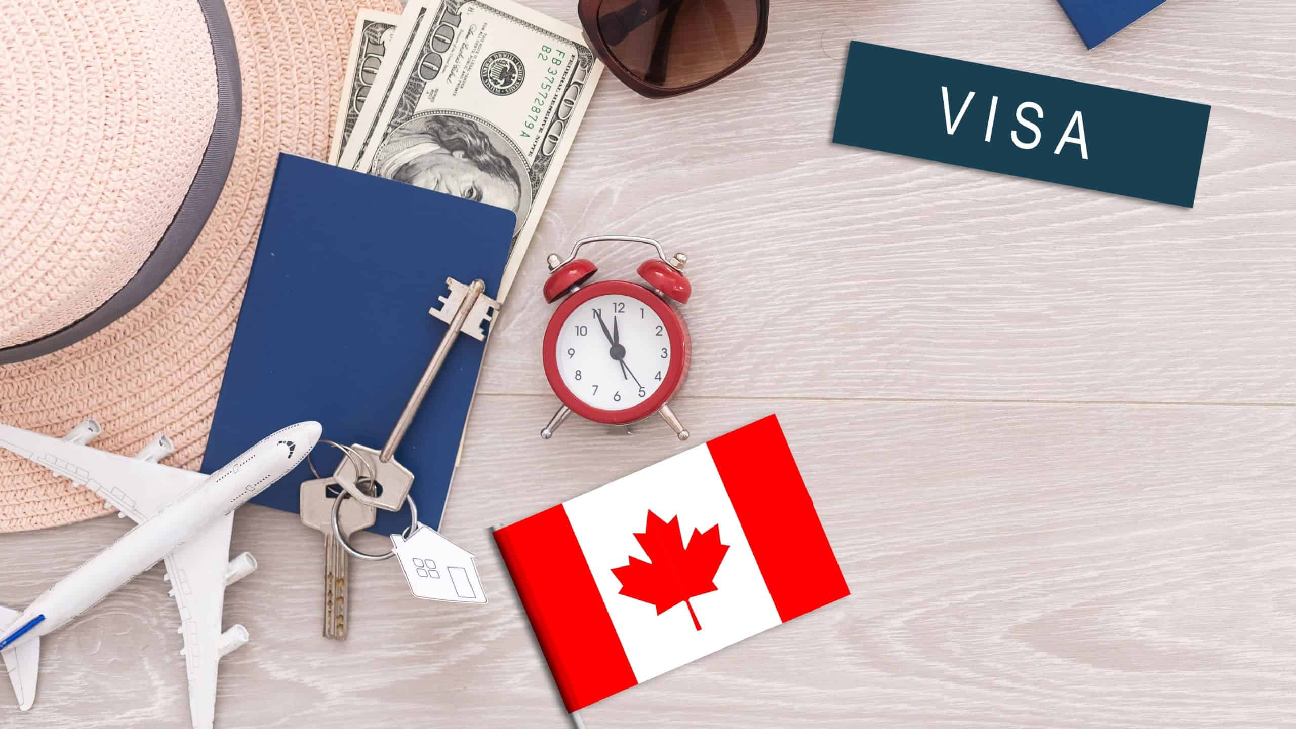 Flag of Canada with passport and toy airplane on wooden background. Flight travel concept