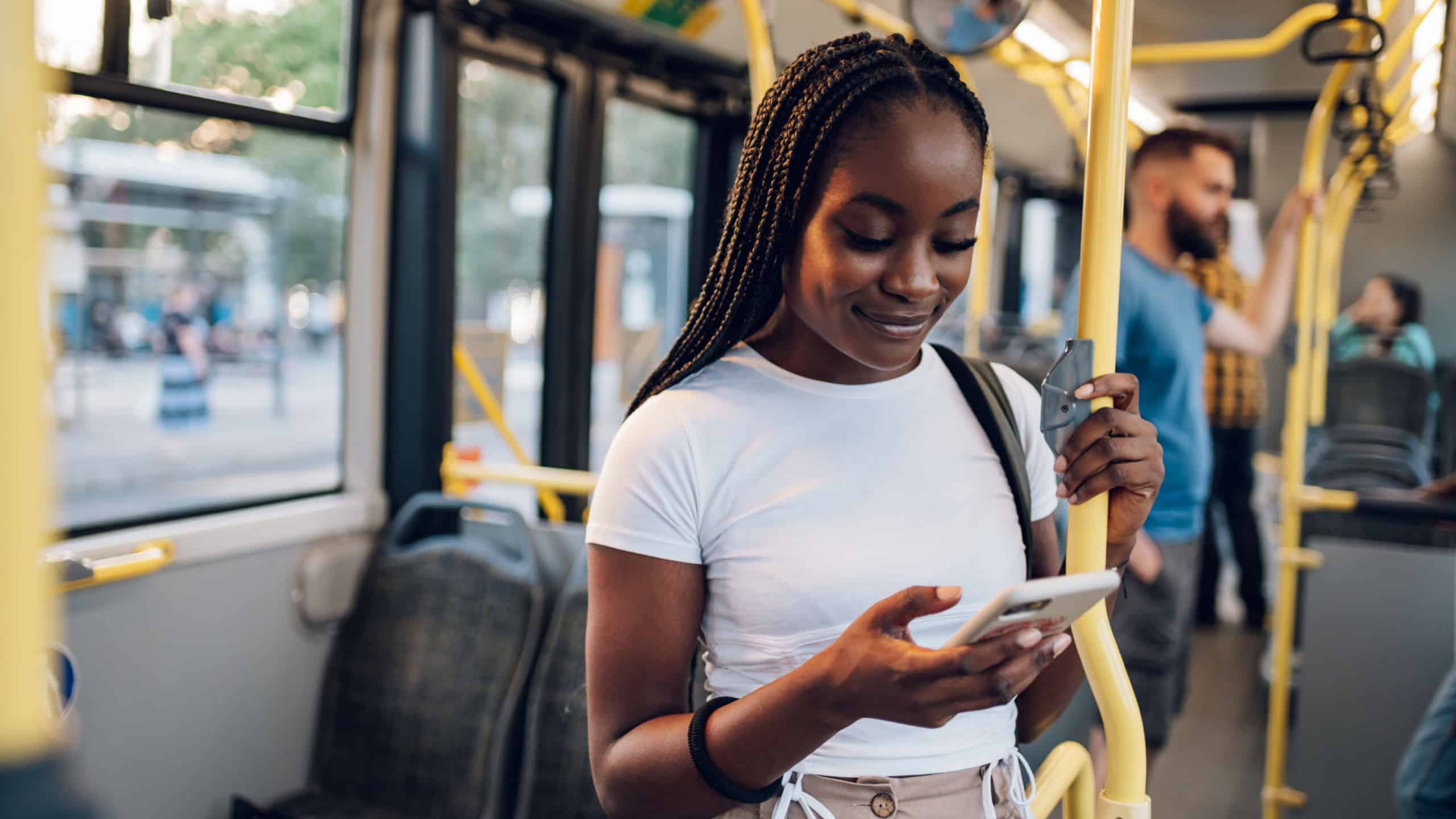 Portrait of a beautiful young African american woman using a smartphone while standing alone on a bus. Traveling to work and enjoying a bus ride. Black female using public transportation. Copy space.