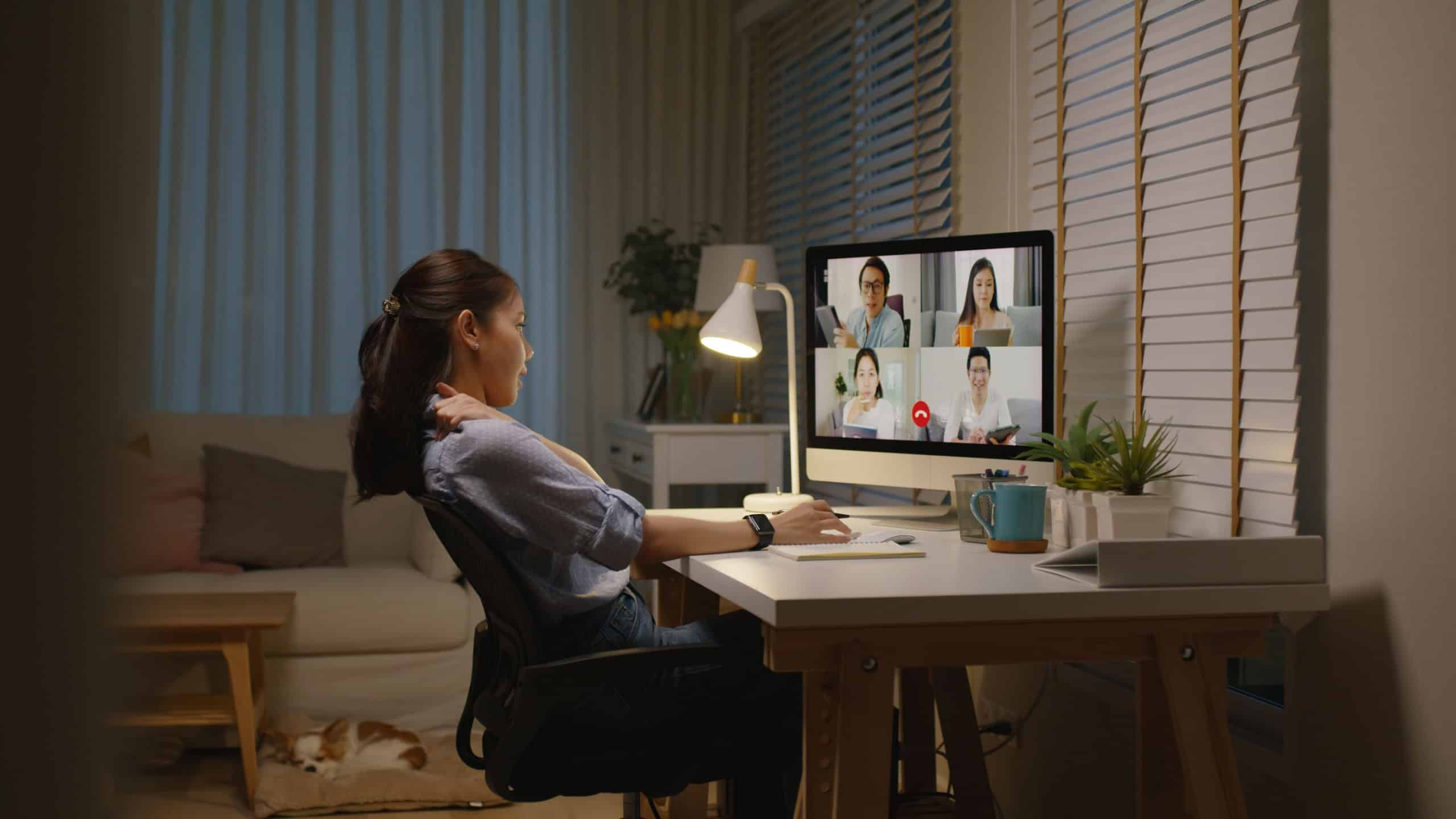 Young asia female busy late night work hard video call online remote group talk stiff neck relief pain ache sit on desk computer in chronic suffer burnout brownout office syndrome workforce at home.