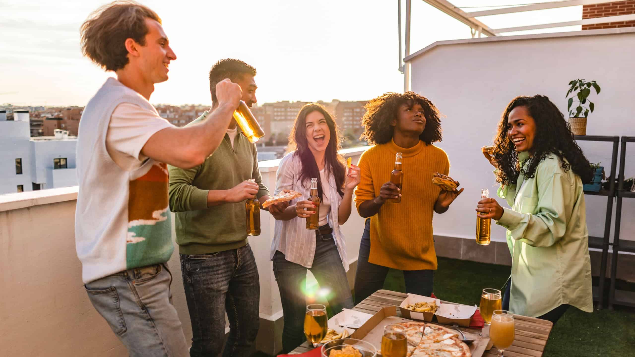 Group of multiracial millennial friends on rooftop party
