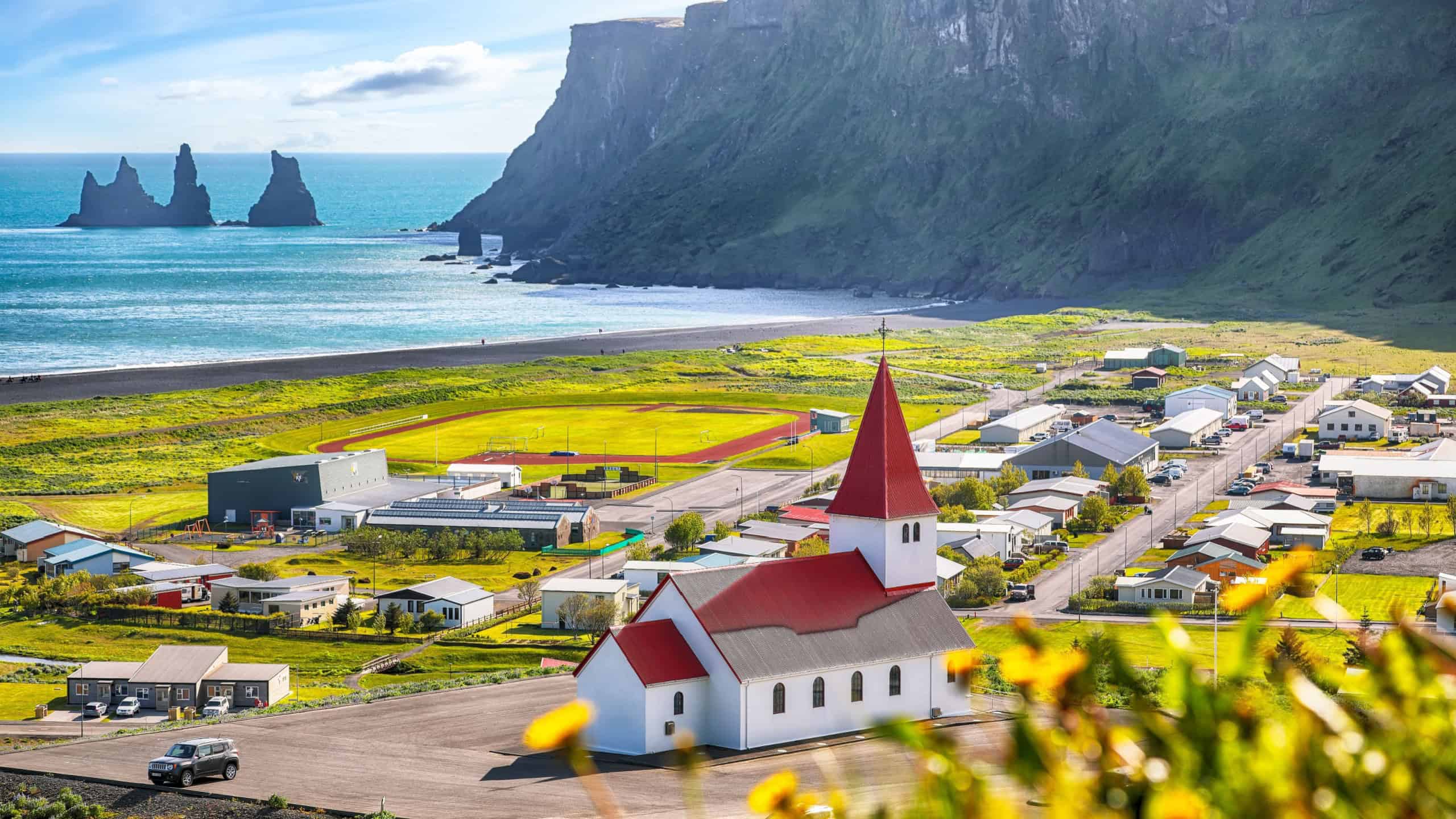 Breathtaking view of Vikurkirkja christian church in blooming flowers. Most popular tourist destination. Location: Vik village in Myrdal Valley, Iceland, Europe.