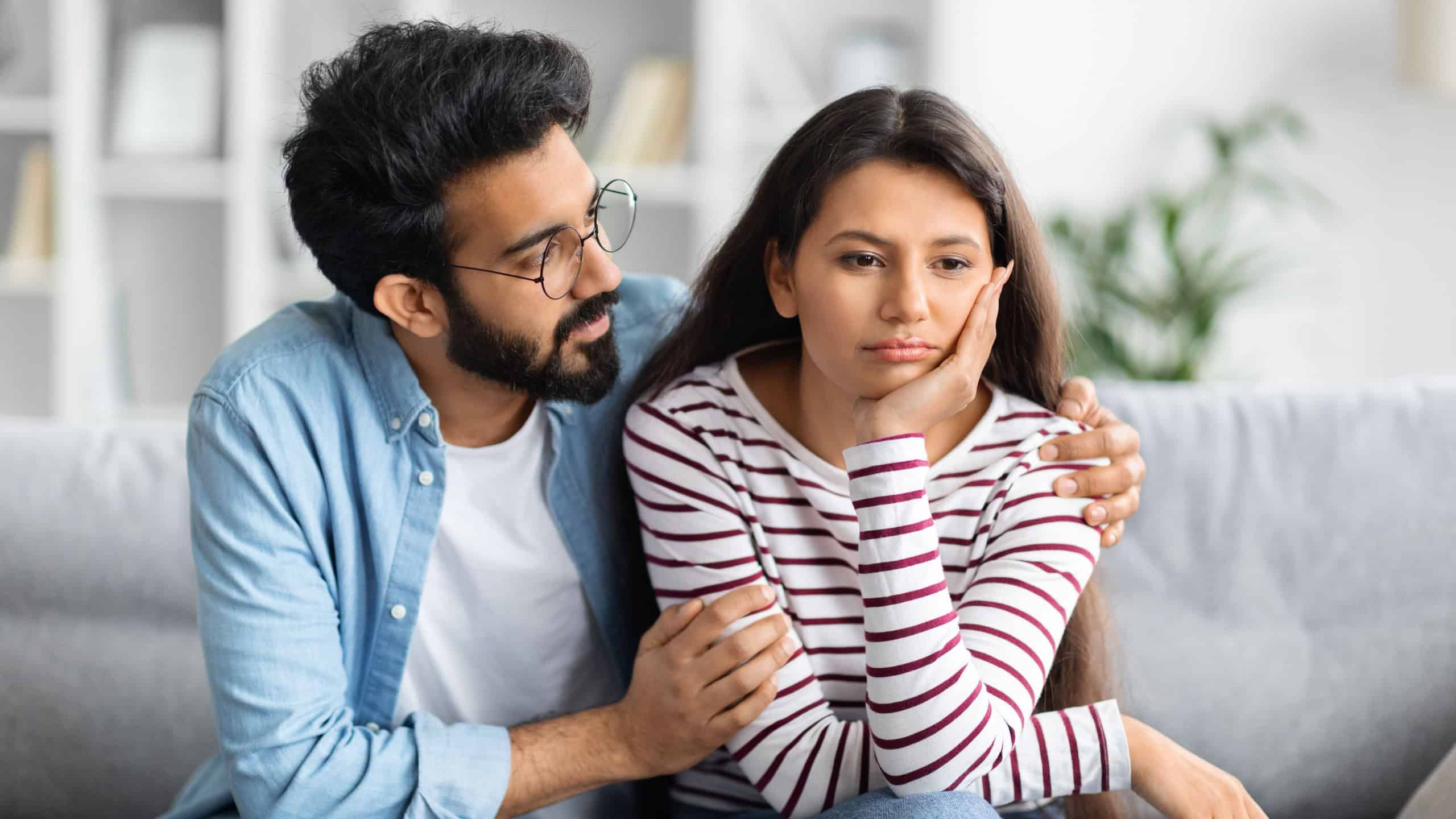 Compassionate eastern husband giving comfort, support to upset wife, holding shoulders, speaking expressing empathy. Man feeling guilty, asking girlfriend to forgive. Relationship, compassion concept