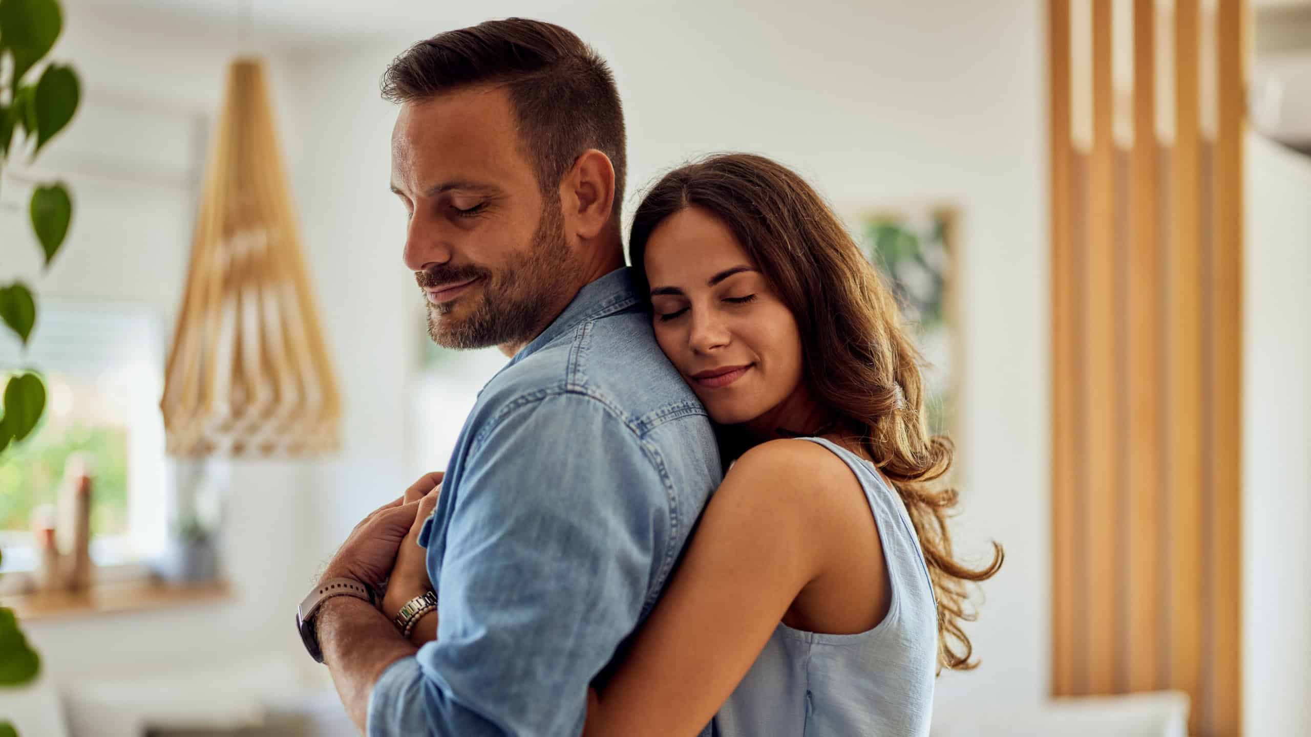 A couple in love enjoying a hug in the morning at home, feeling peaceful.