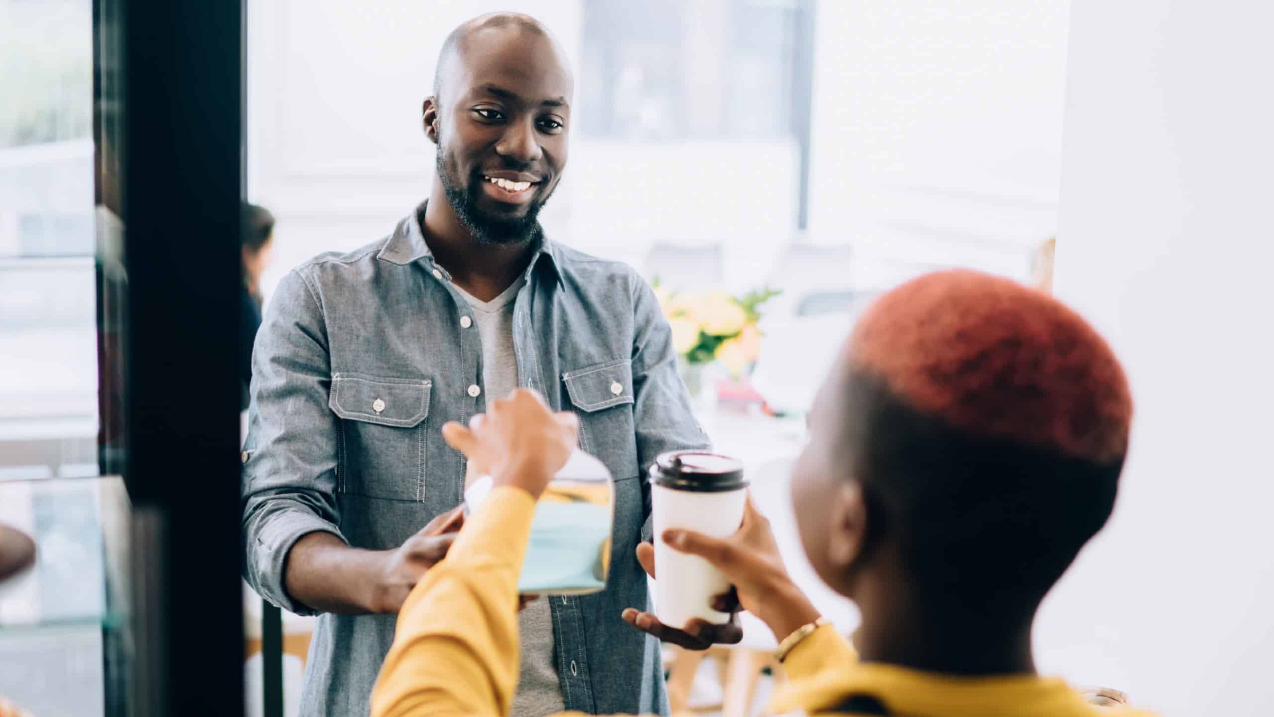 Positive black guy buying coffee and cake in bakery