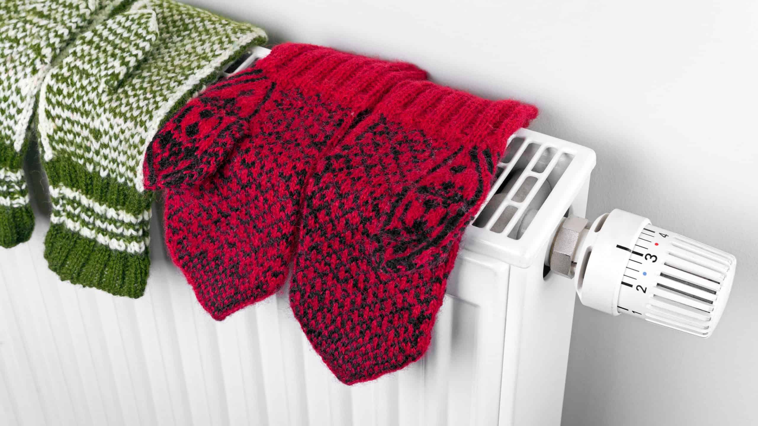 Wool mittens drying on radiator, closeup knitted gloves