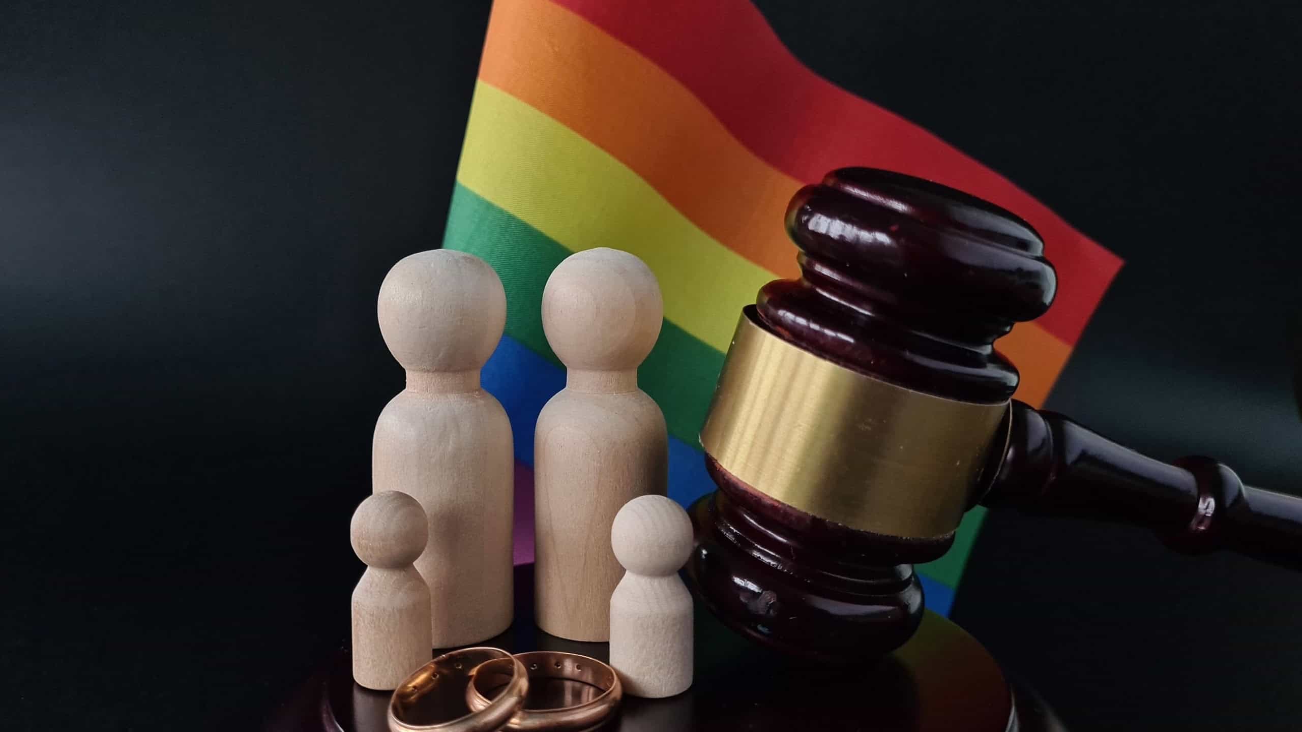 Legalization of same-sex marriage and wedding rings from family. Rainbow flag and judge's gavel and divorce