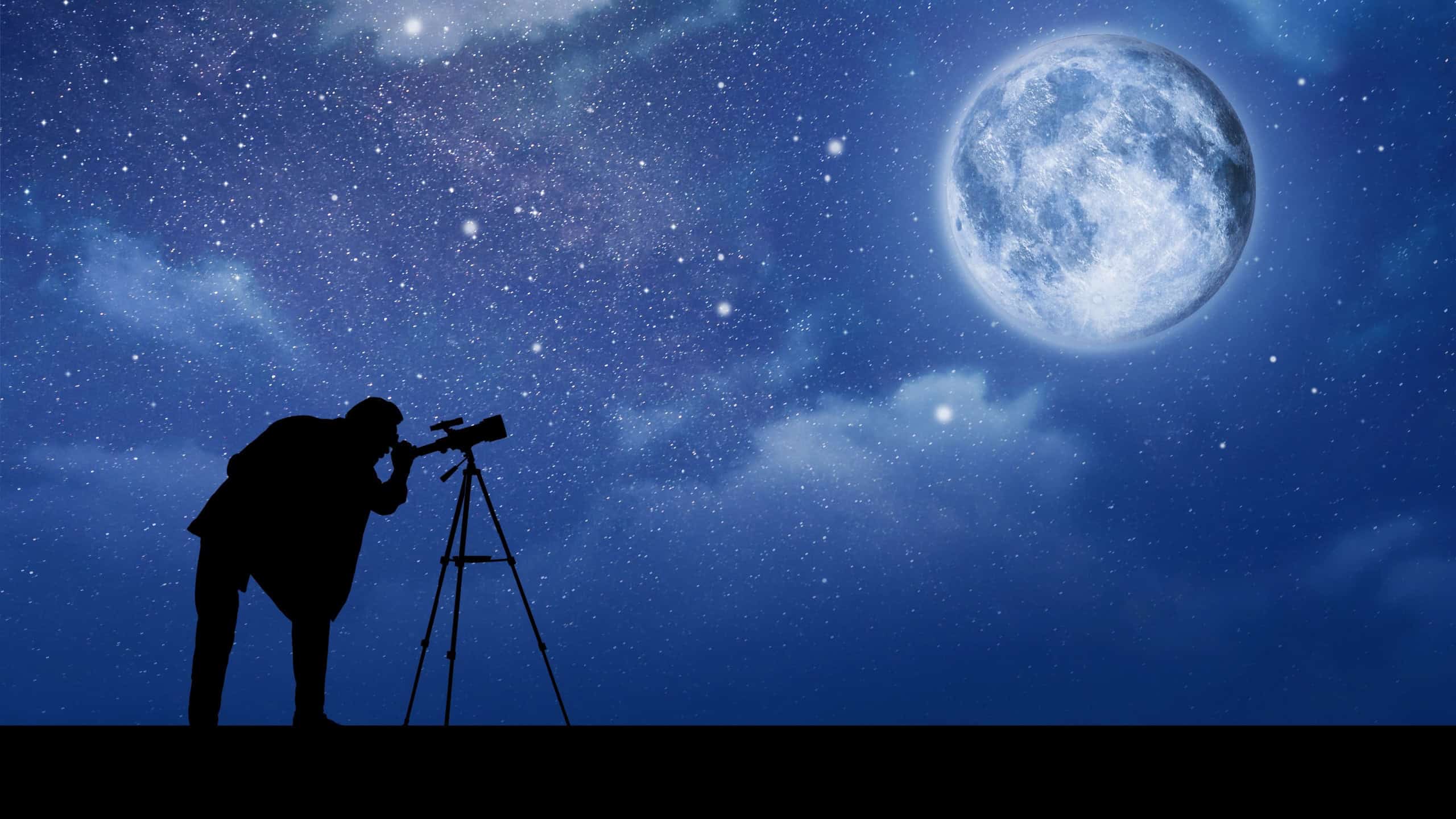 Astronomer looking at moon and stars through telescope outdoors