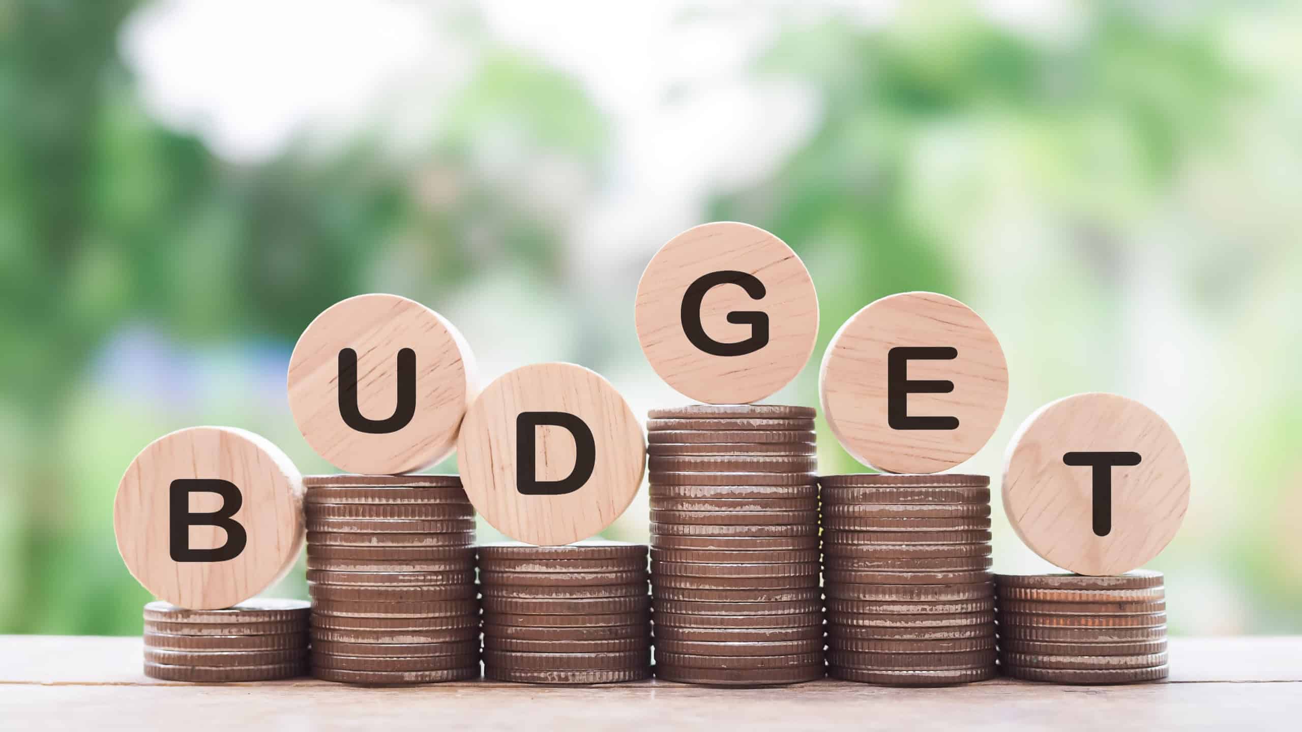 Wooden blocks with the word BUDGET on stack of coins. The concept about budget planning and allocation