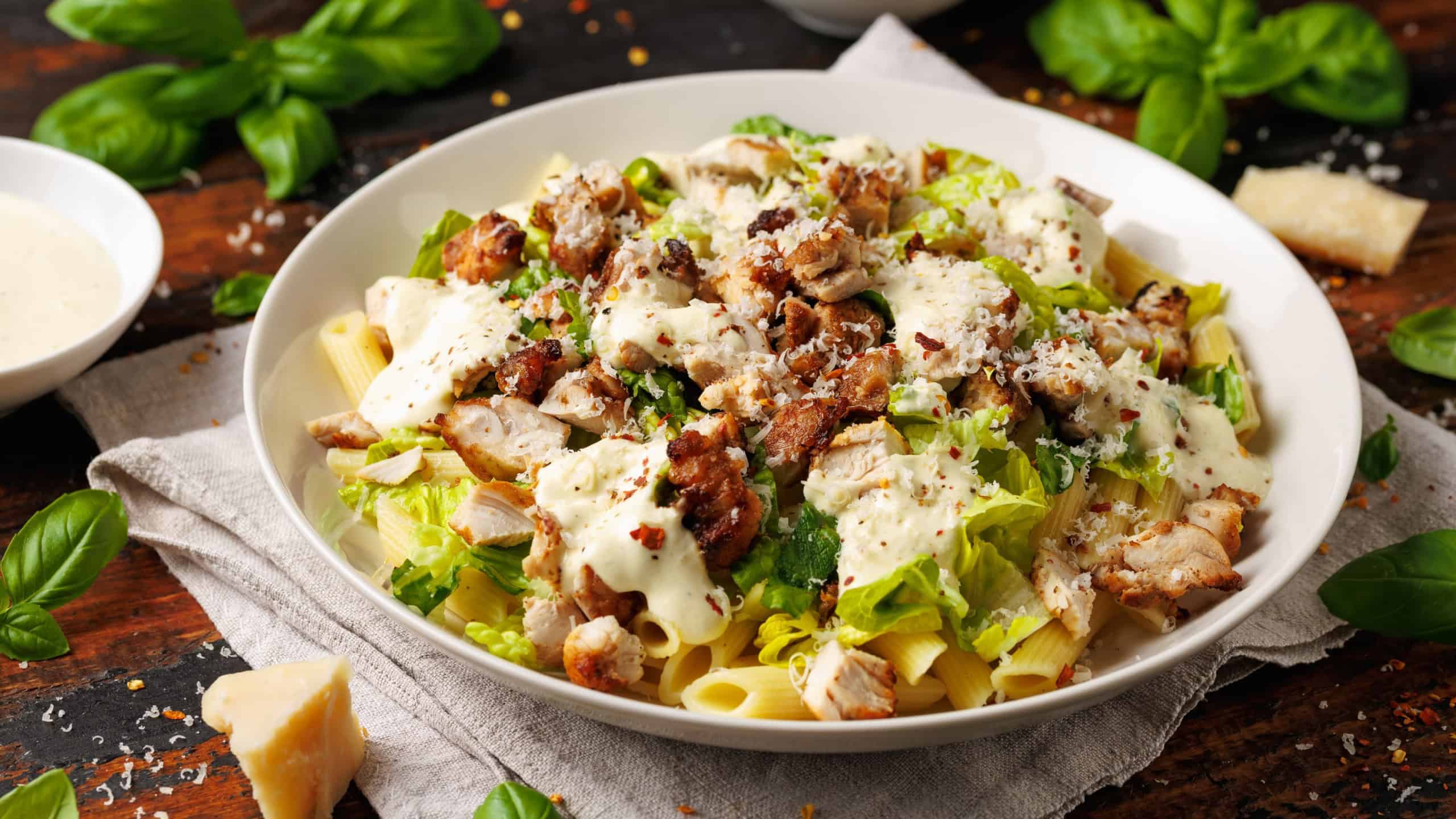 Chicken Caesar Pasta Salad with sauce in white plate. Healthy food.
