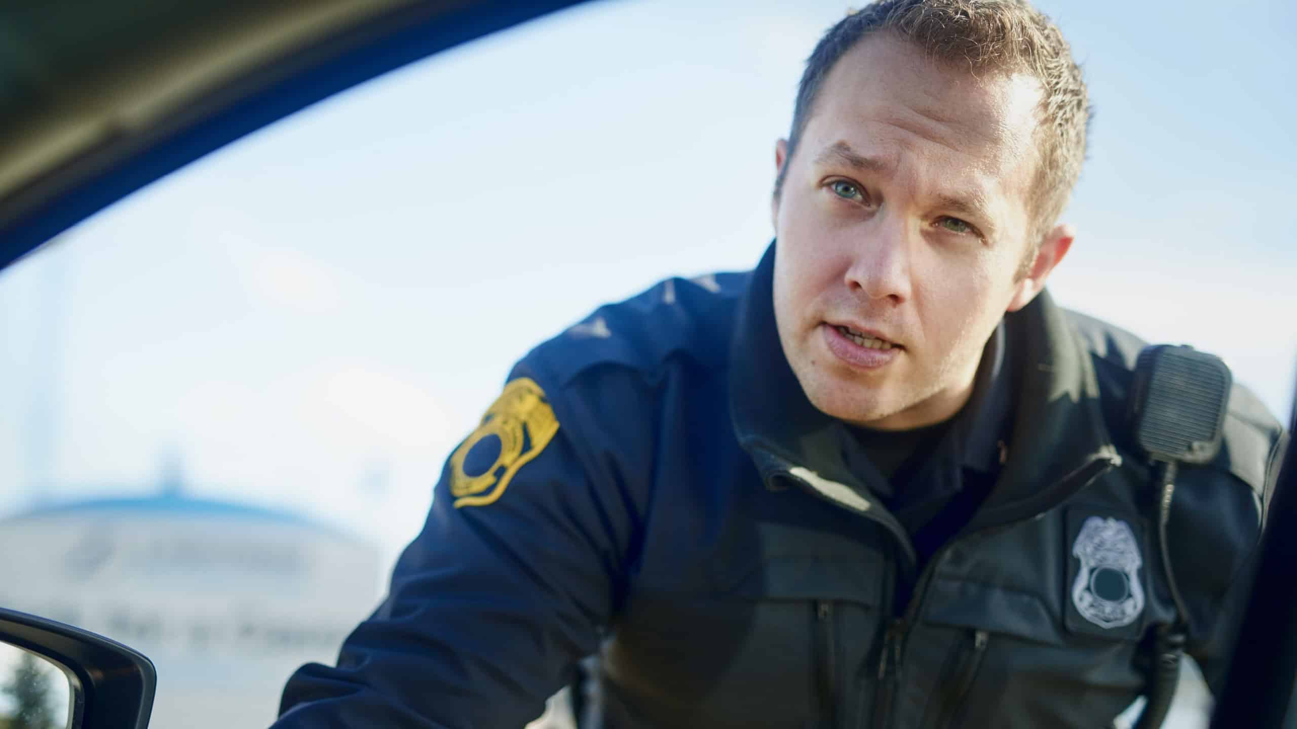 Traffic stop, police officer and talking at car for inspection, license check and law enforcement responsibility in city. Man, cop and question at vehicle window in roadblock, safety or investigation