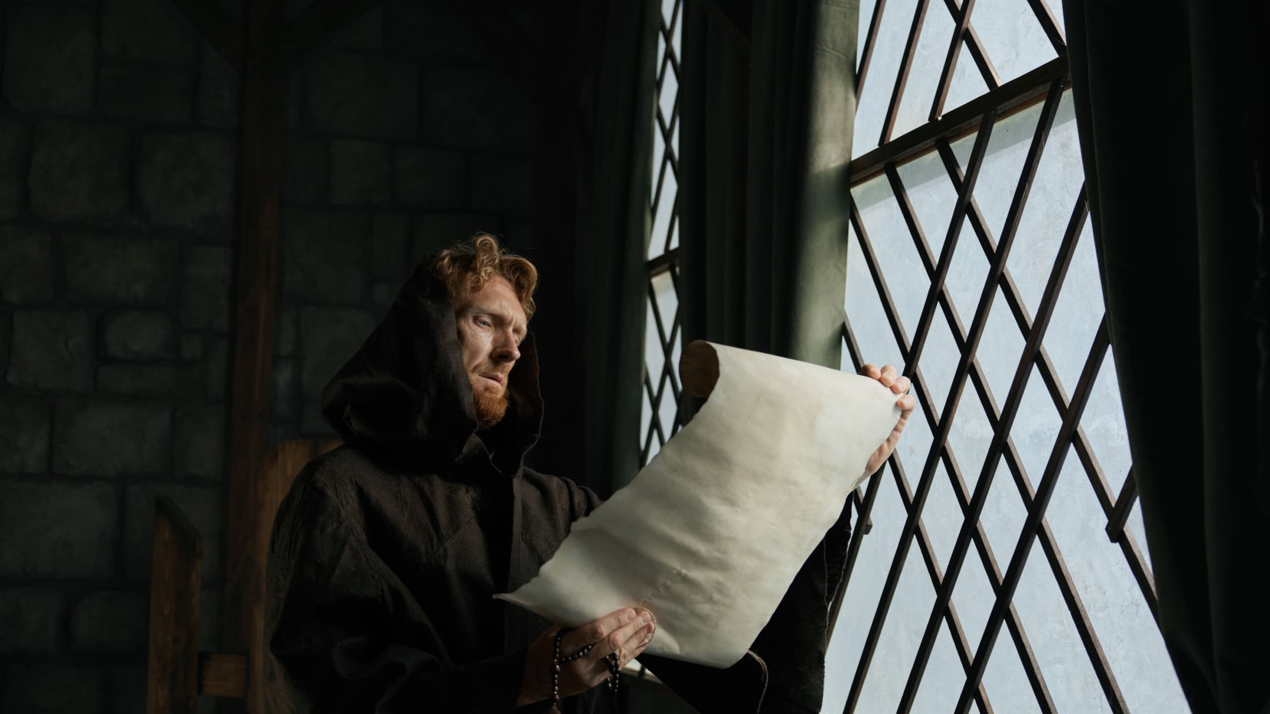 Medieval monk reading obsolete historical parchments and holy manuscripts